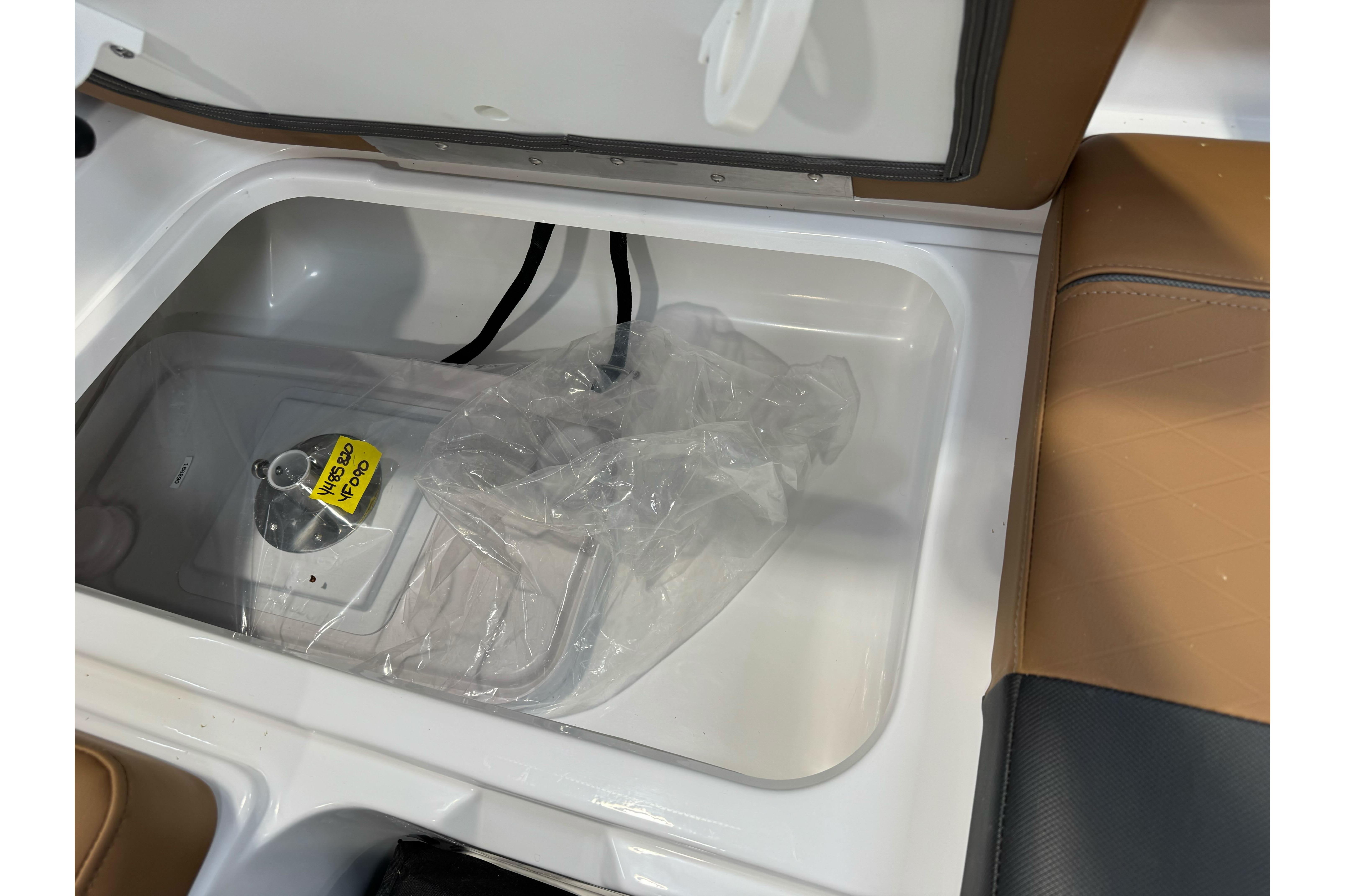 Storage compartment in 2026 Tahoe 2150 boat with plastic-wrapped equipment inside.