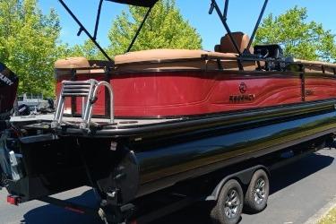 2026 Regency 250 DL pontoon boat on trailer, red and black design, parked outdoors.