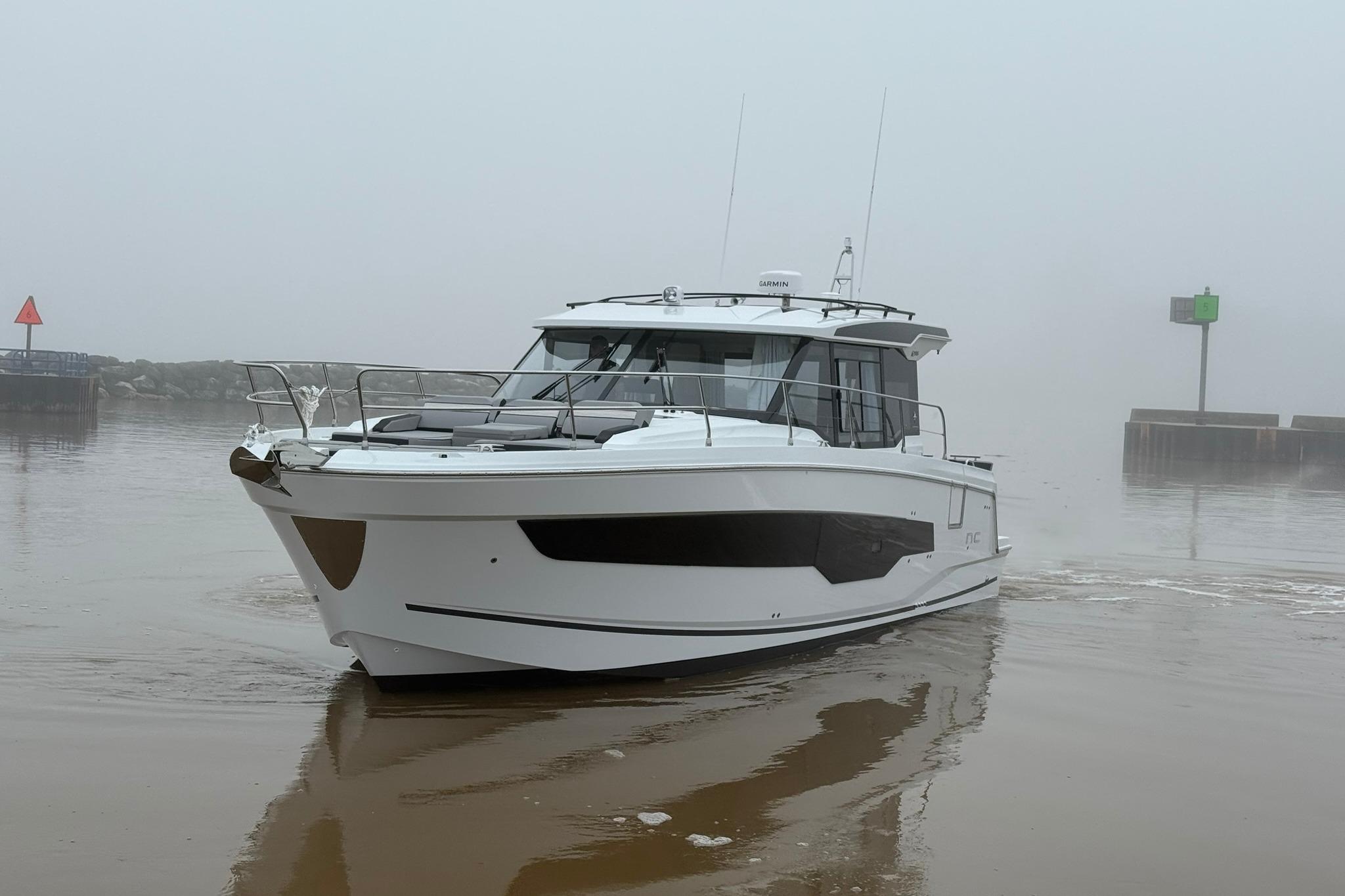 2026 Jeanneau NC 1295 Coupe boat navigating through foggy waters.