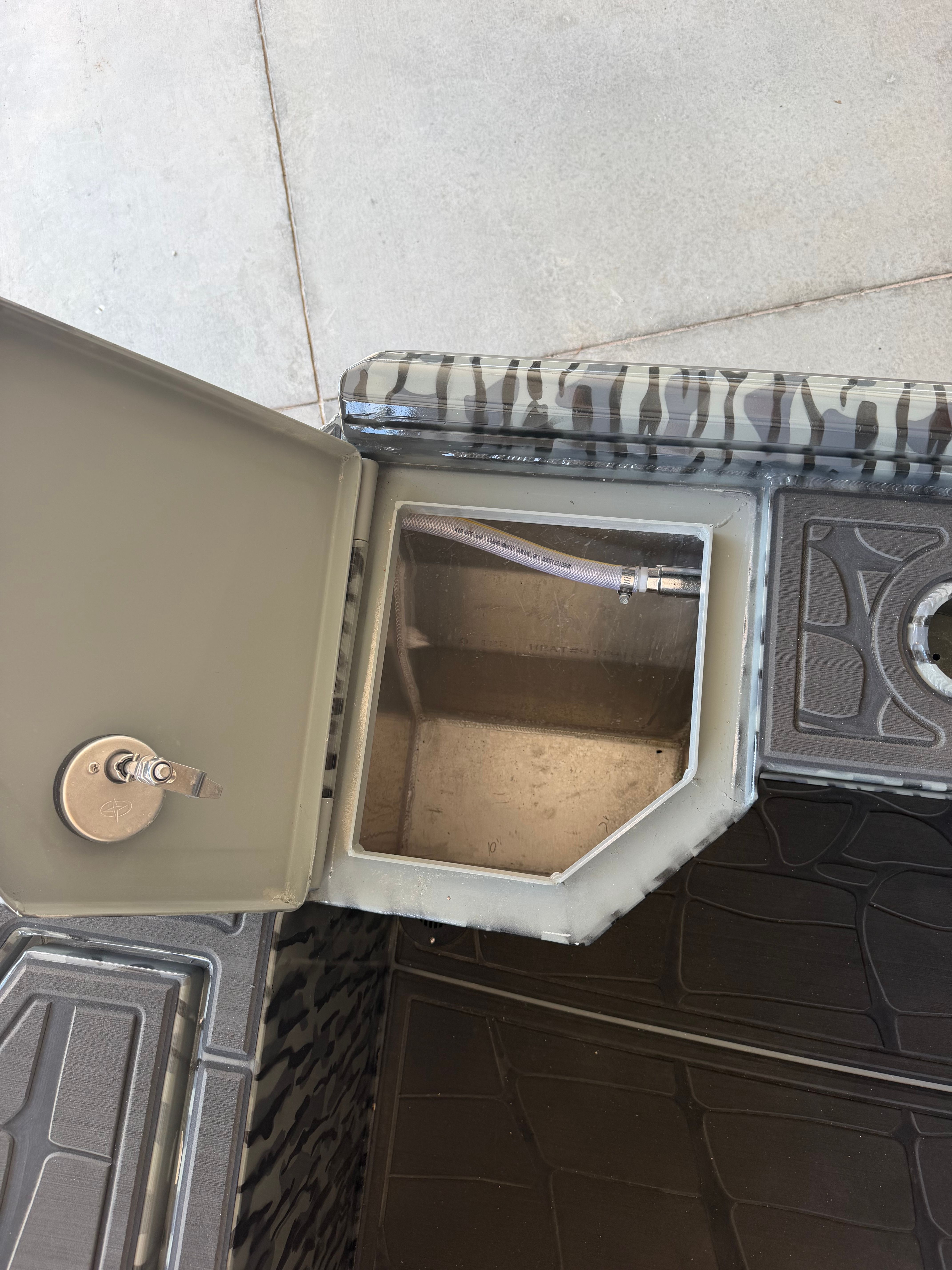 An open compartment on a boat with a hose and a lock.