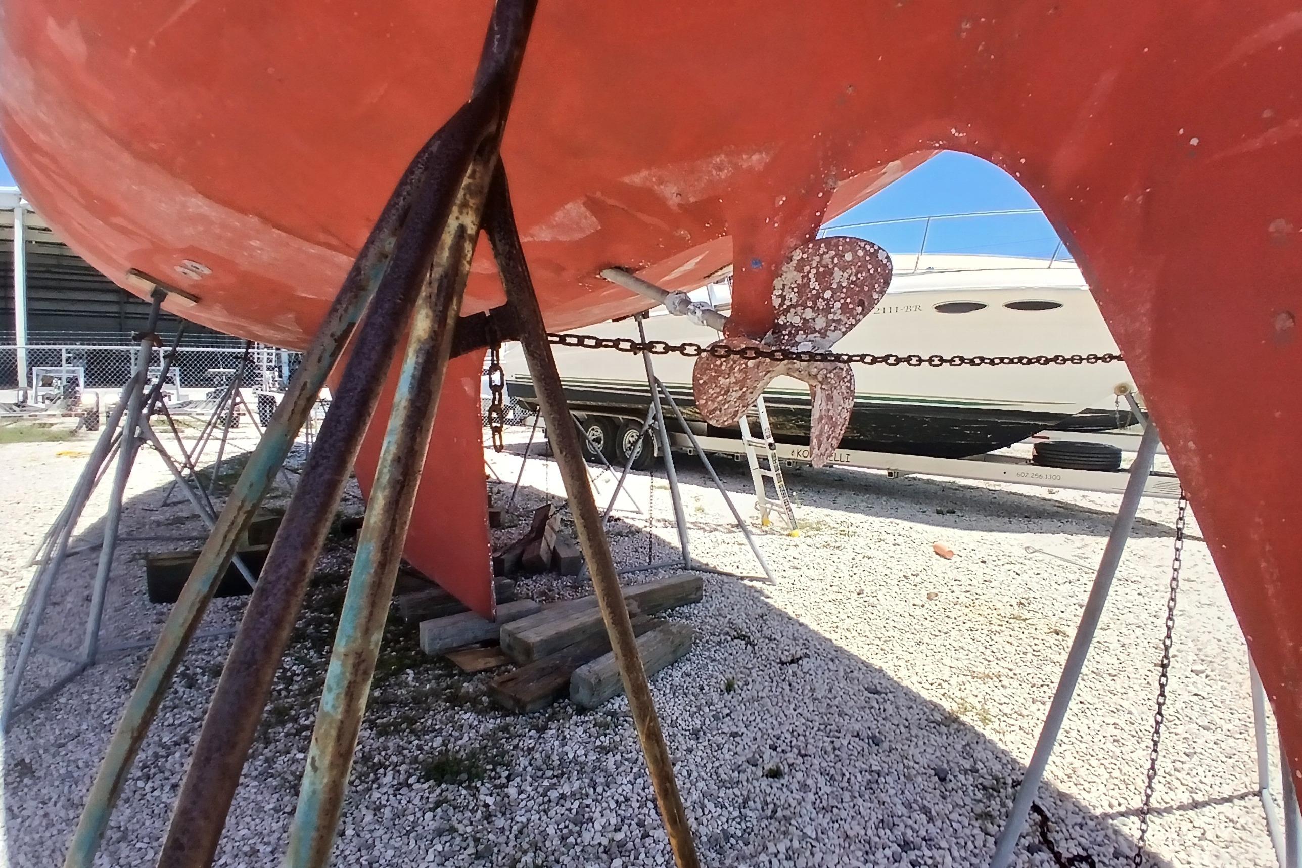 1981 Kaufman Skye 51 sailboat on stands, showing propeller and hull in a boatyard.