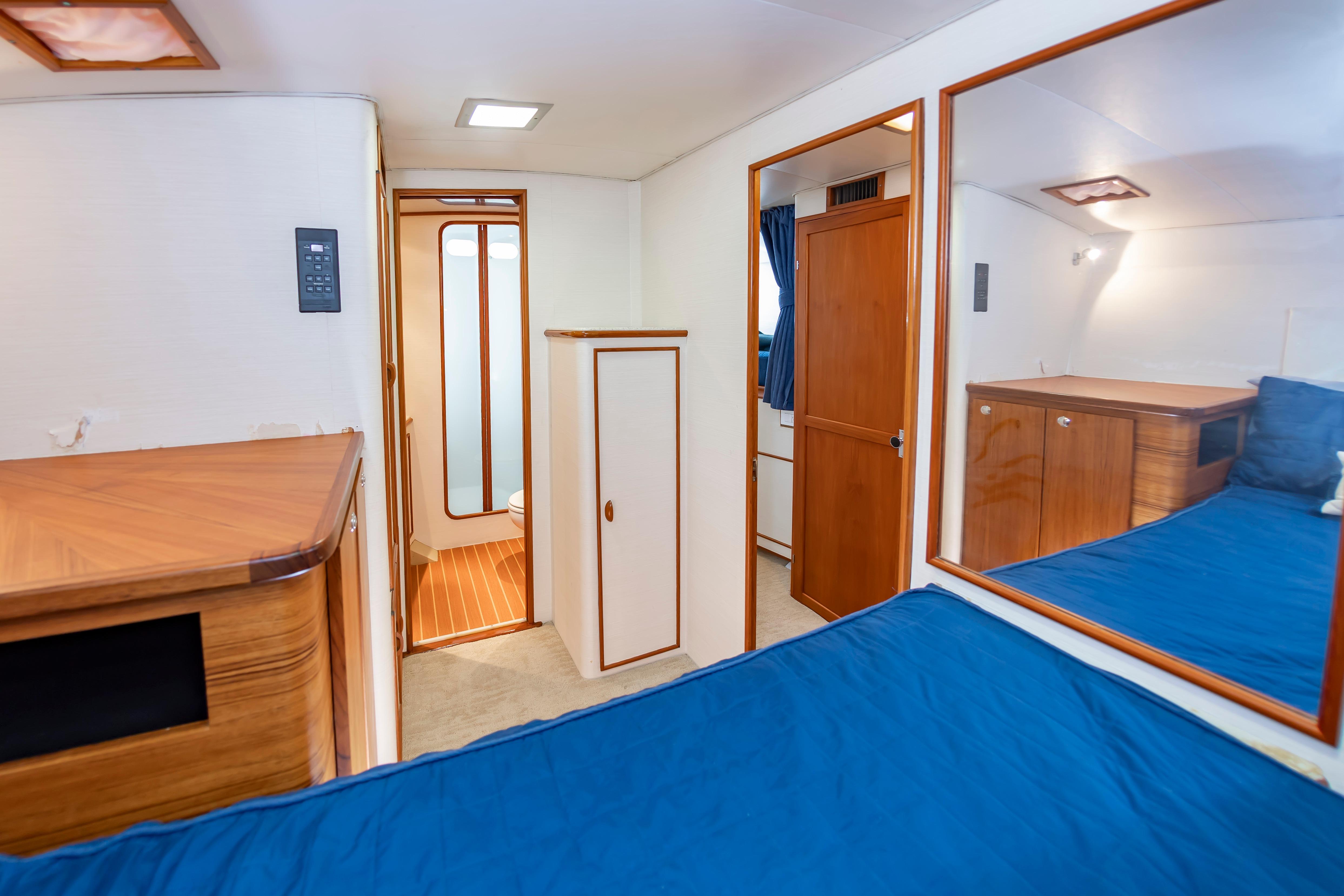 Interior of 1993 Custom Carolina Scarborough 56 Convertible yacht, featuring wood accents and blue bedding.