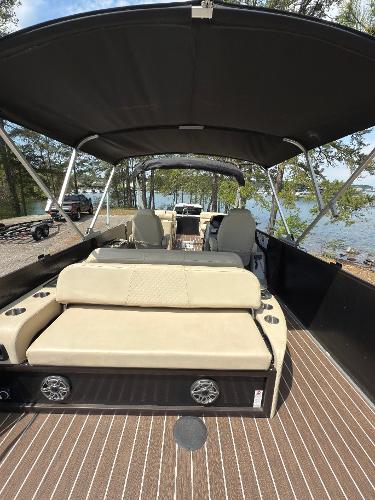 2022 Premier 250 Solaris boat with beige seating, canopy, and wood-style flooring by a lakeside.