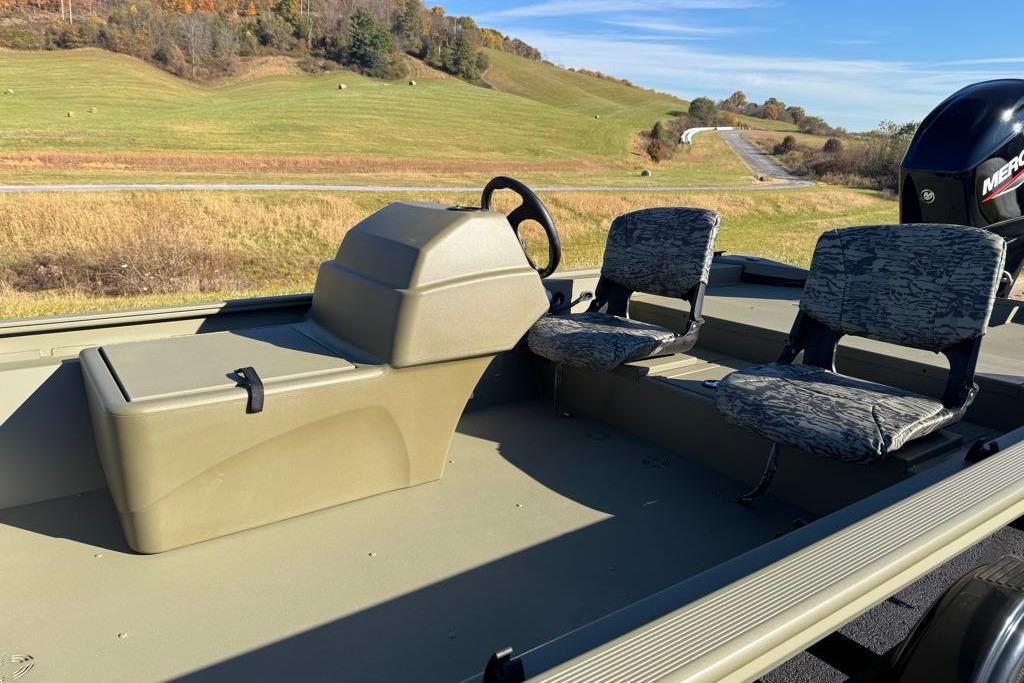 2026 Tracker Grizzly 1754 SC boat interior with seating, steering console, and scenic background.