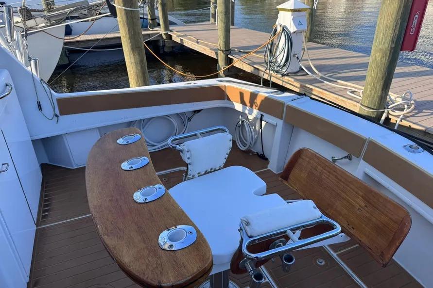 1981 Hatteras 43 Convertible boat deck with wooden seating and fishing rod holders.