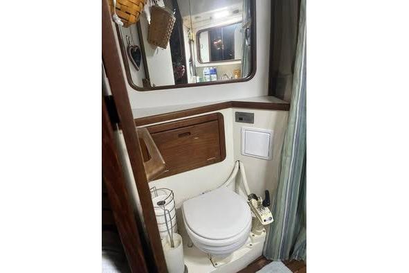 1989 Catalina 42 yacht bathroom with toilet, mirror, and wooden cabinetry.