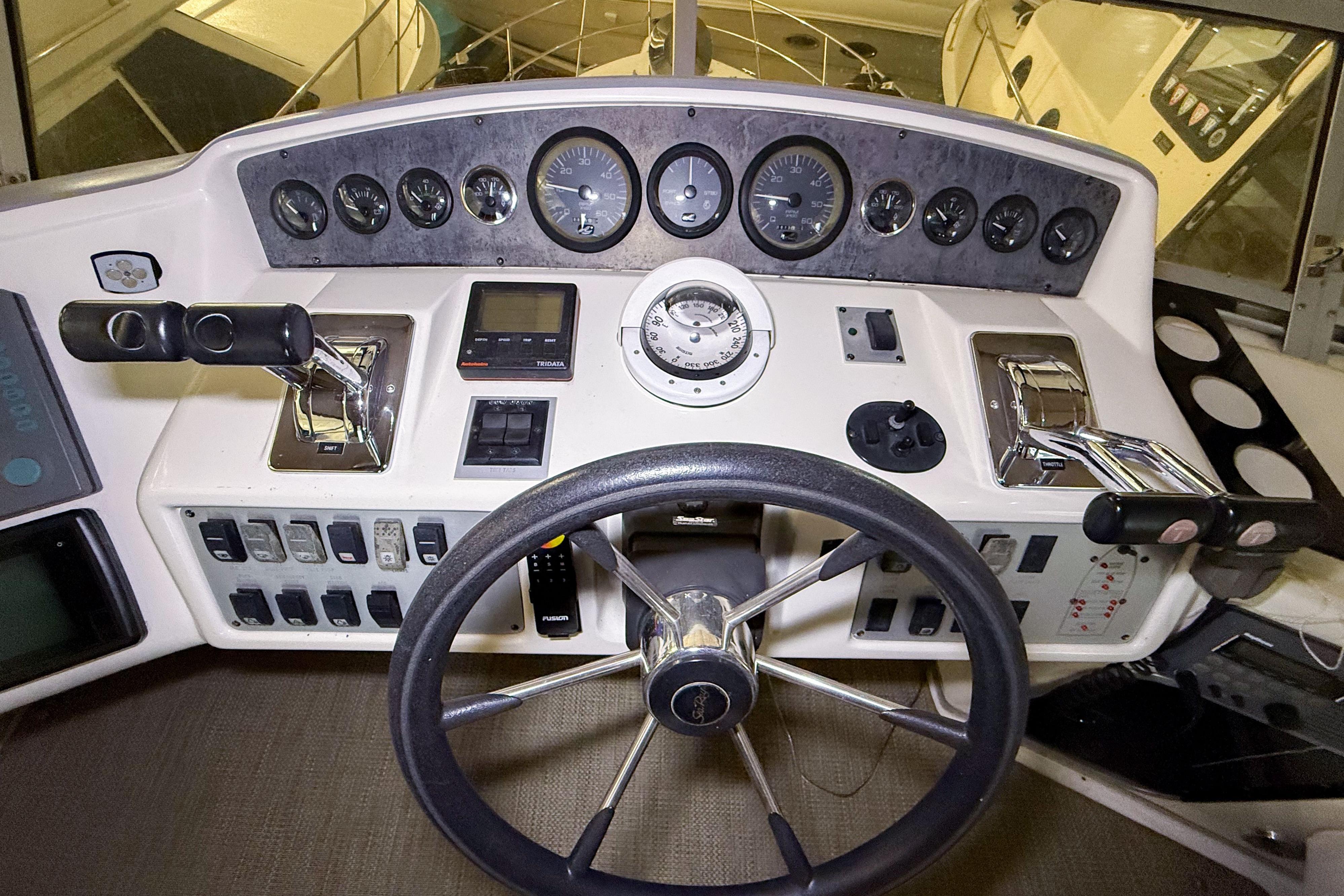 1995 Sea Ray 370 Sedan Bridge helm with gauges, steering wheel, and controls.