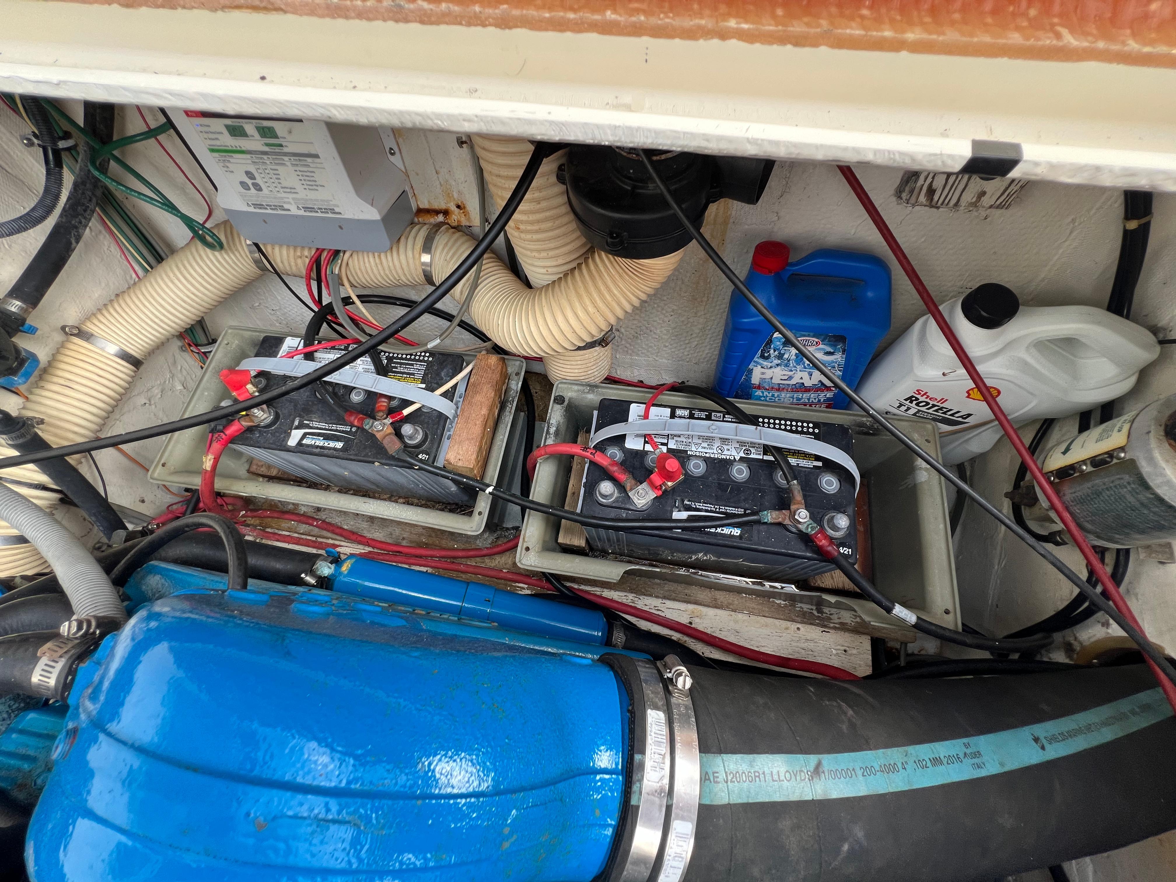 Engine compartment of 1990 Bertram 28 Flybridge with batteries and maintenance supplies.