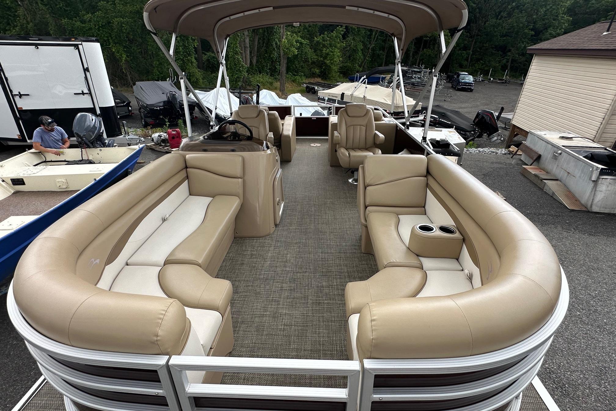 2016 Bennington 24 SCWX pontoon boat with beige seating and canopy, parked outdoors.