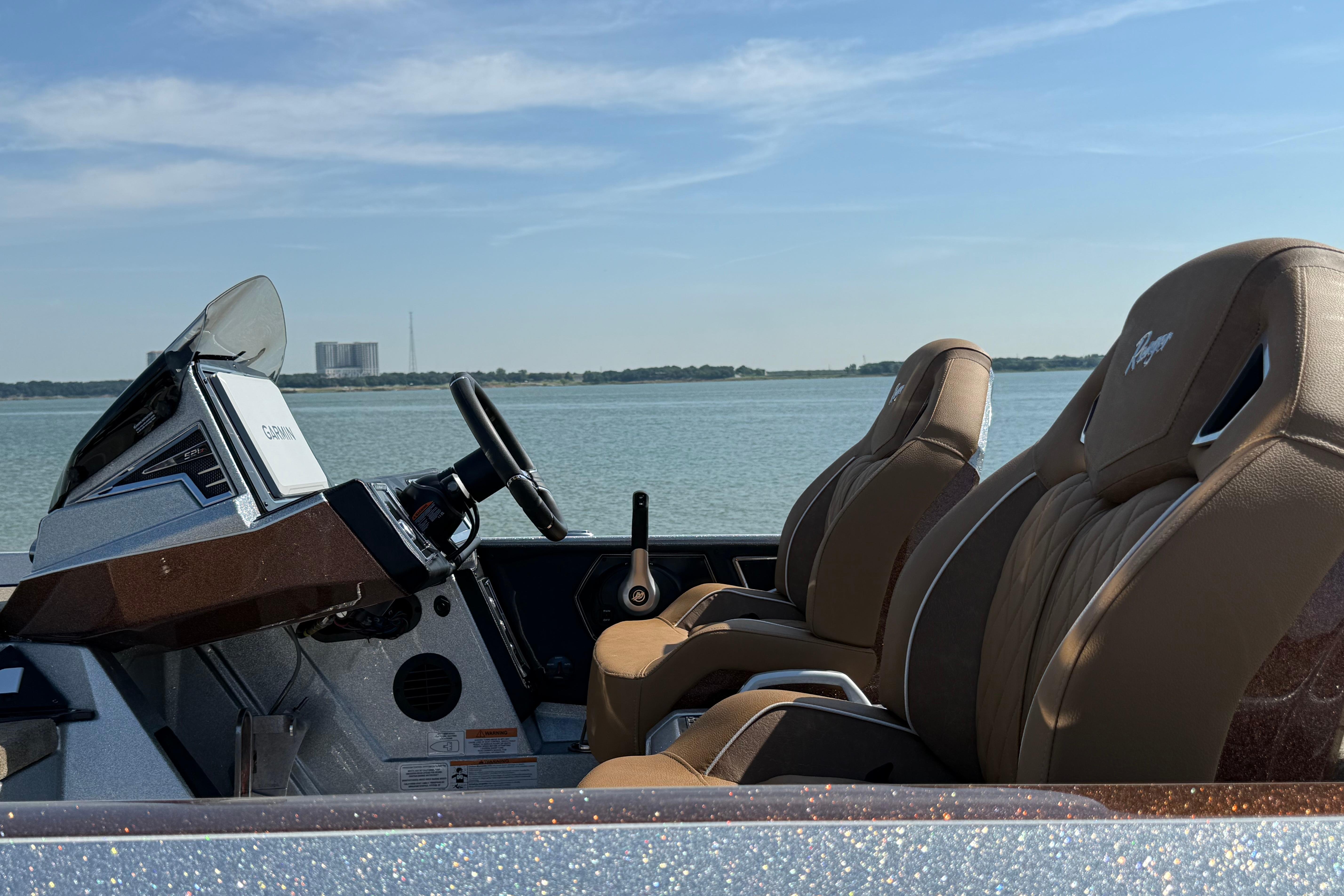 2026 Ranger Z521R boat interior with brown seats, steering wheel, and Garmin display on a lake.