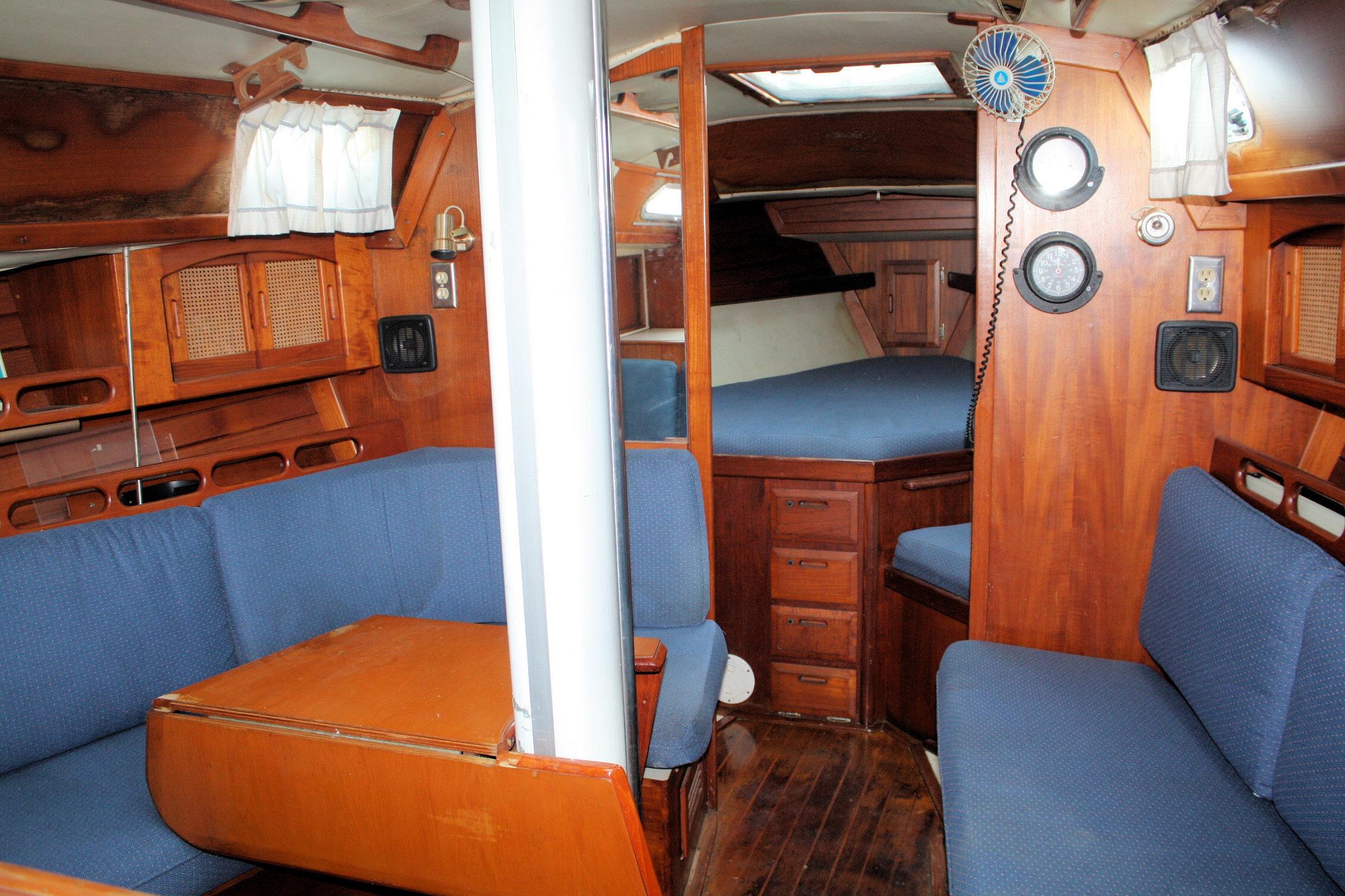 Interior of 1987 Ericson 38-200 sailboat with blue seating and wooden cabinetry.