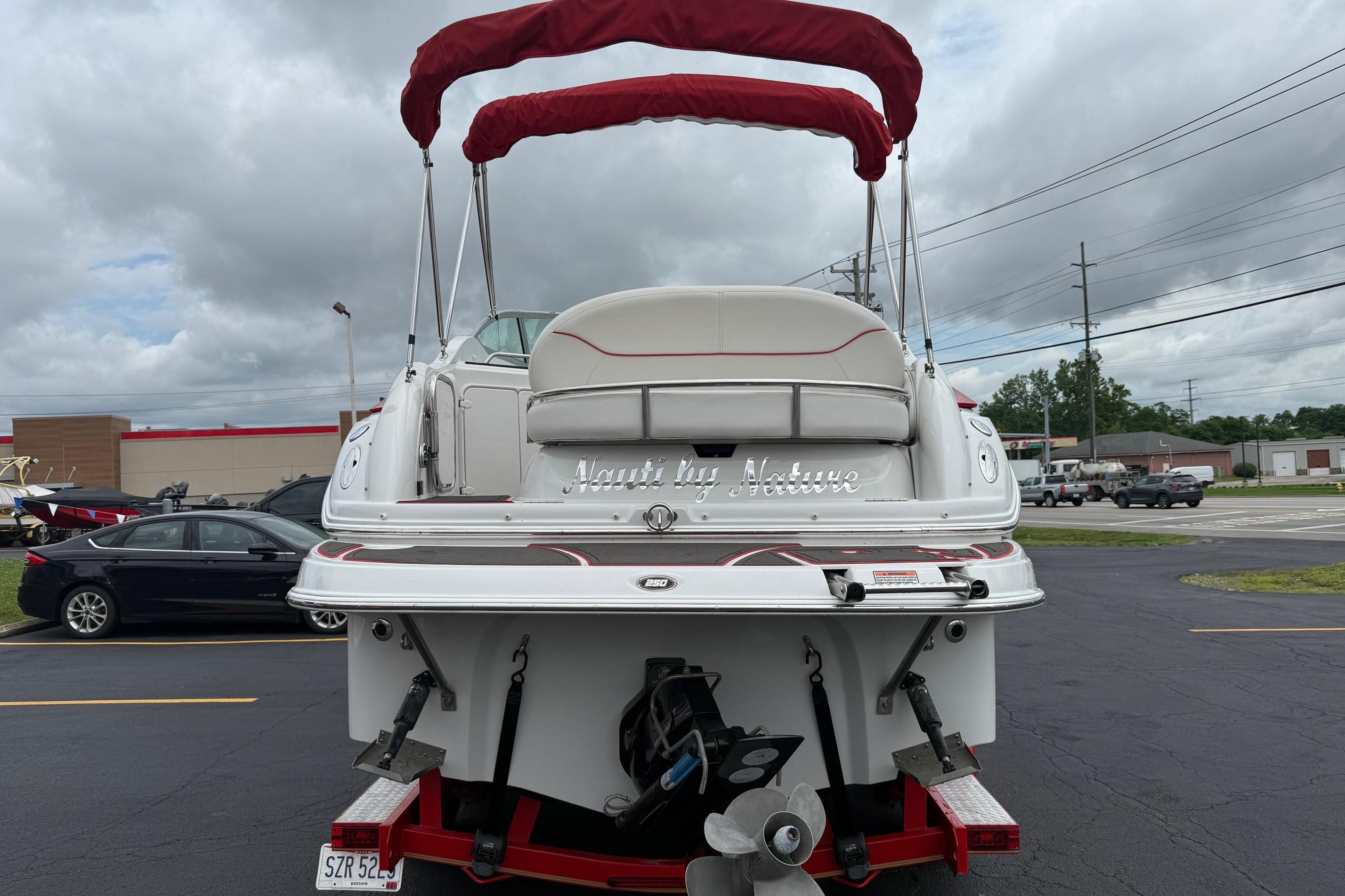 2005 Crownline 250 CR boat with red canopy, parked in a lot.