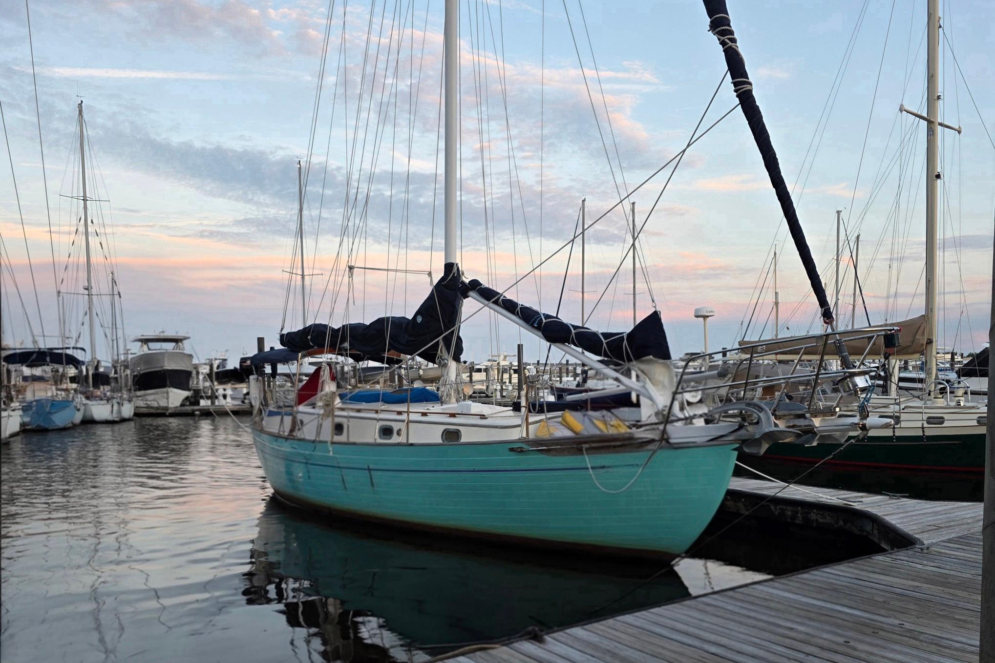 1982 Tayana 37 sailboat docked at marina during sunset, surrounded by other boats.