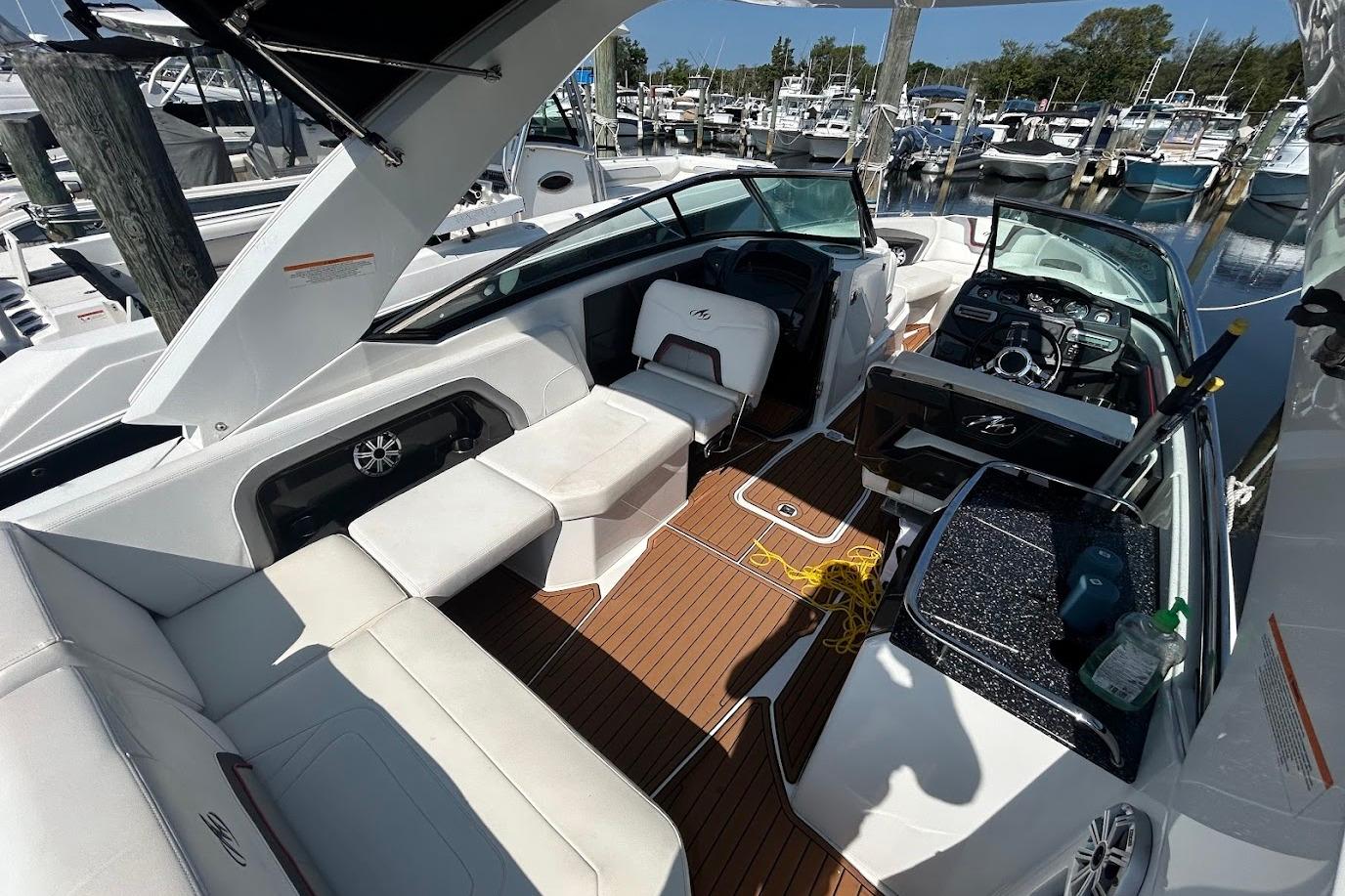2015 Monterey 288 Super Sport boat interior with white seating and wood flooring at a marina.