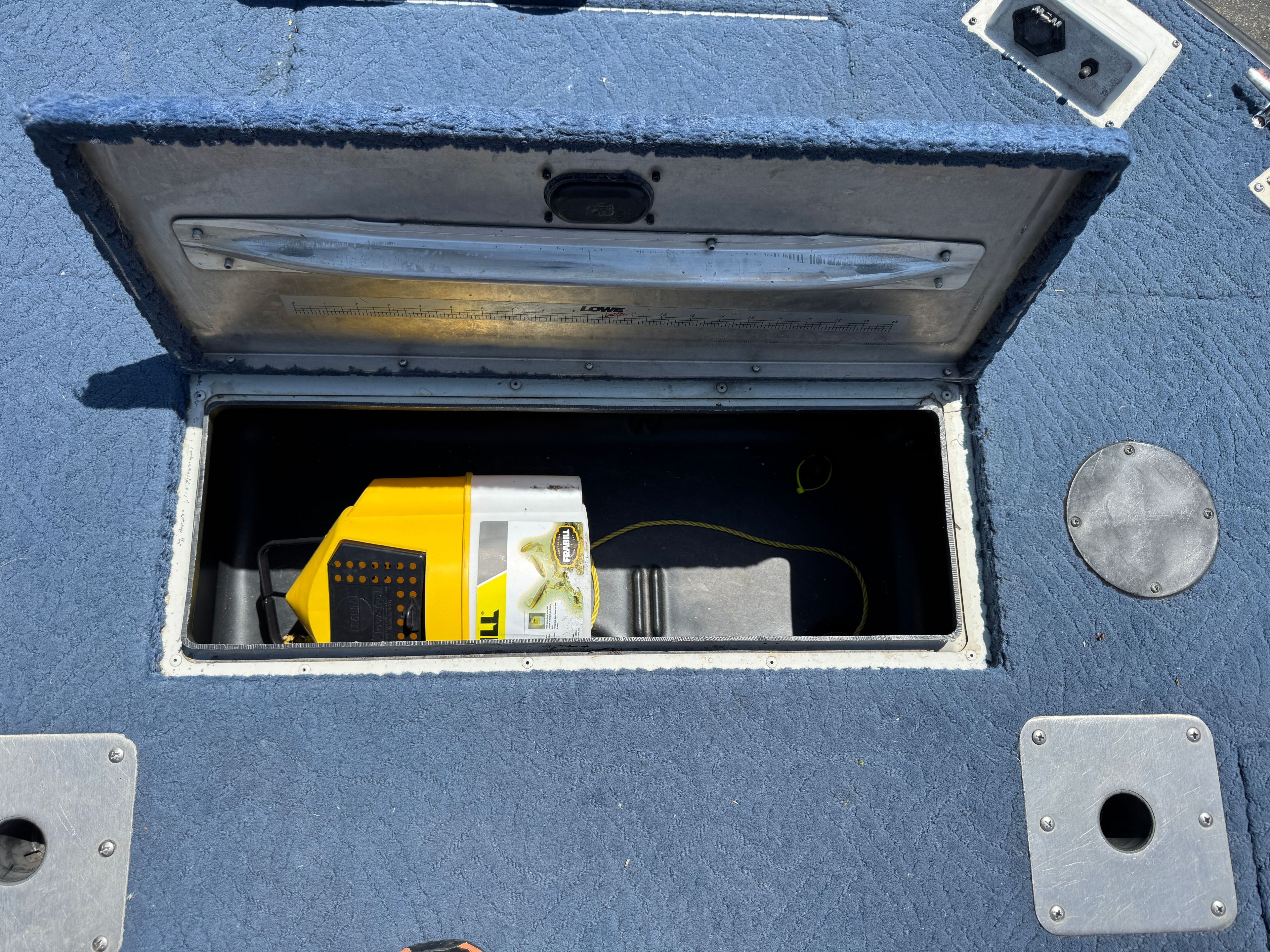 An open storage compartment on a boat with a yellow device inside.