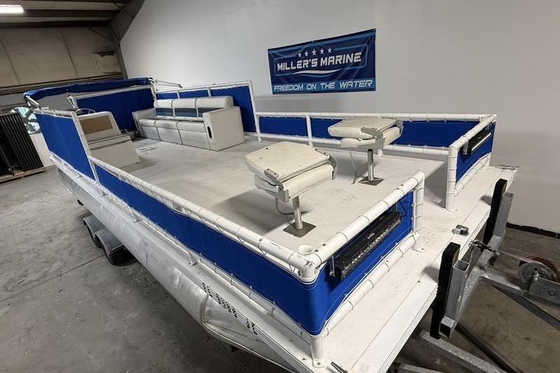 1993 Monark Sun Caster 240 CR 4 Point pontoon boat in showroom, blue and white design.