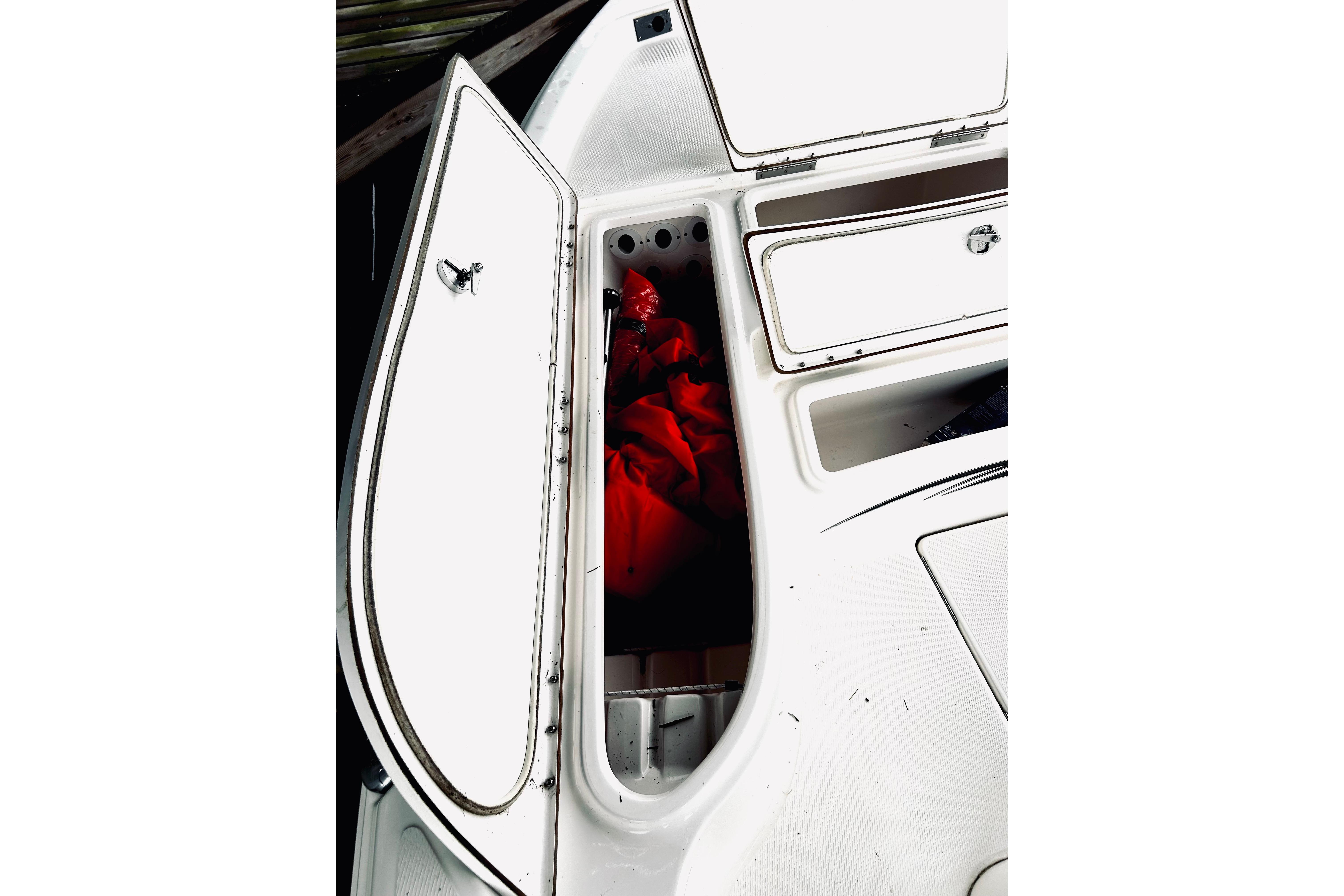 Open storage compartment on 2017 Blue Wave 2200 PureBay boat, revealing red life jacket.