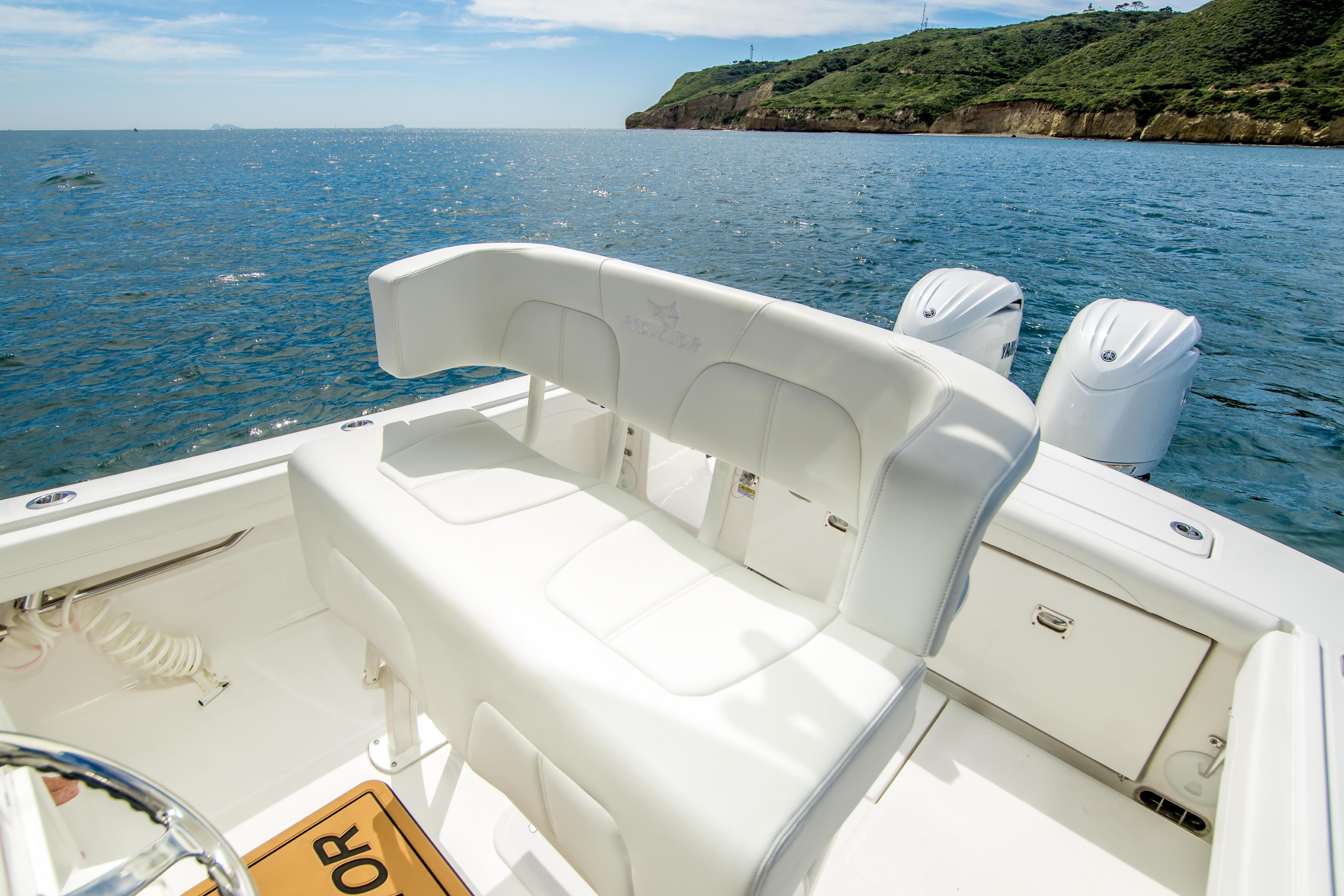 2026 Regulator 23 boat with white seating, dual engines, and scenic ocean view.