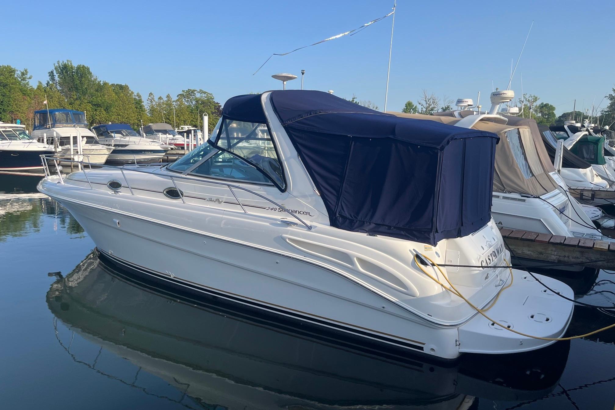 2001 Sea Ray 340 Sundancer boat docked at marina, featuring blue canopy and sleek design.