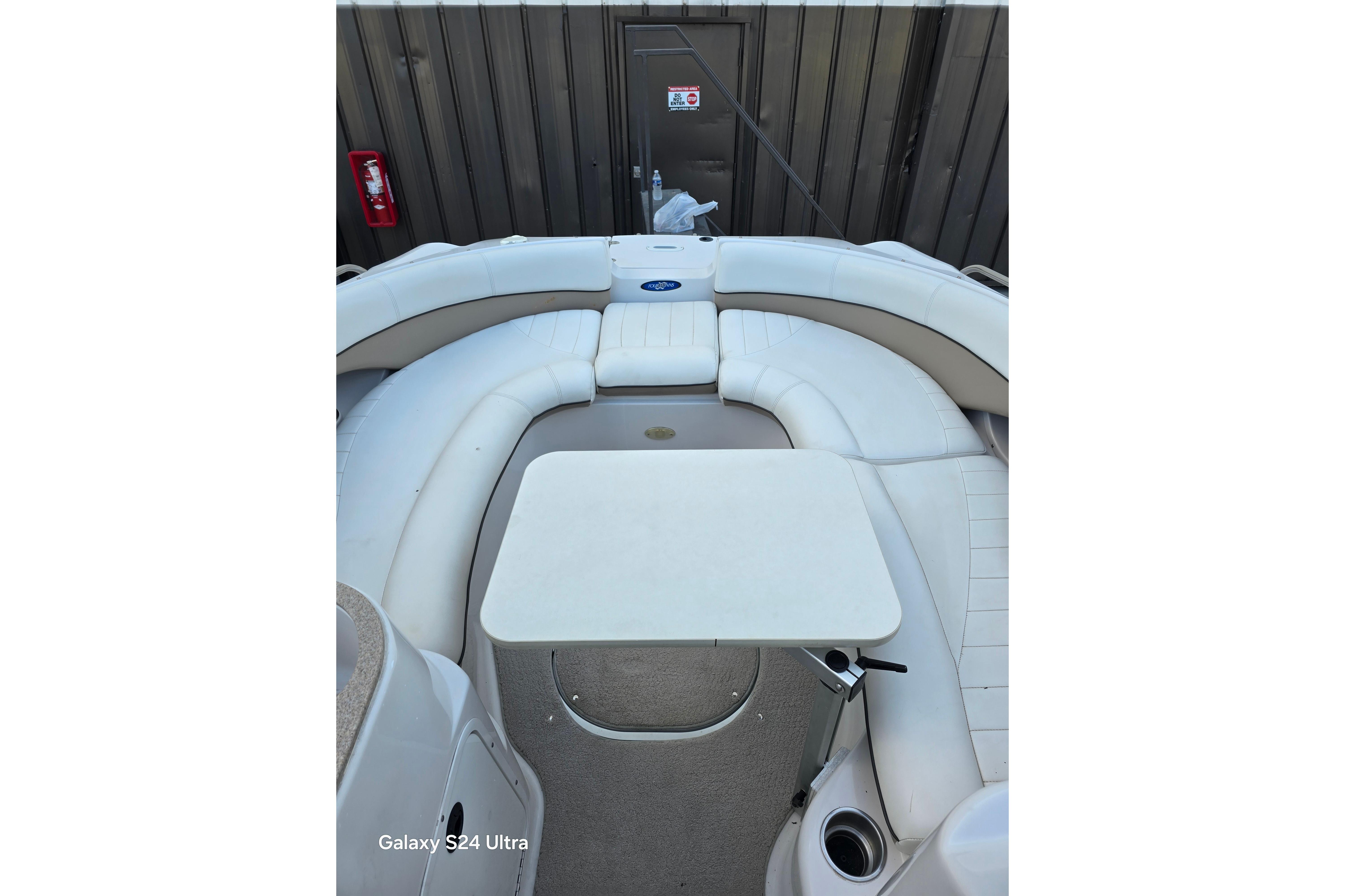 2006 Four Winns 244 Funship boat interior with white seating and table.