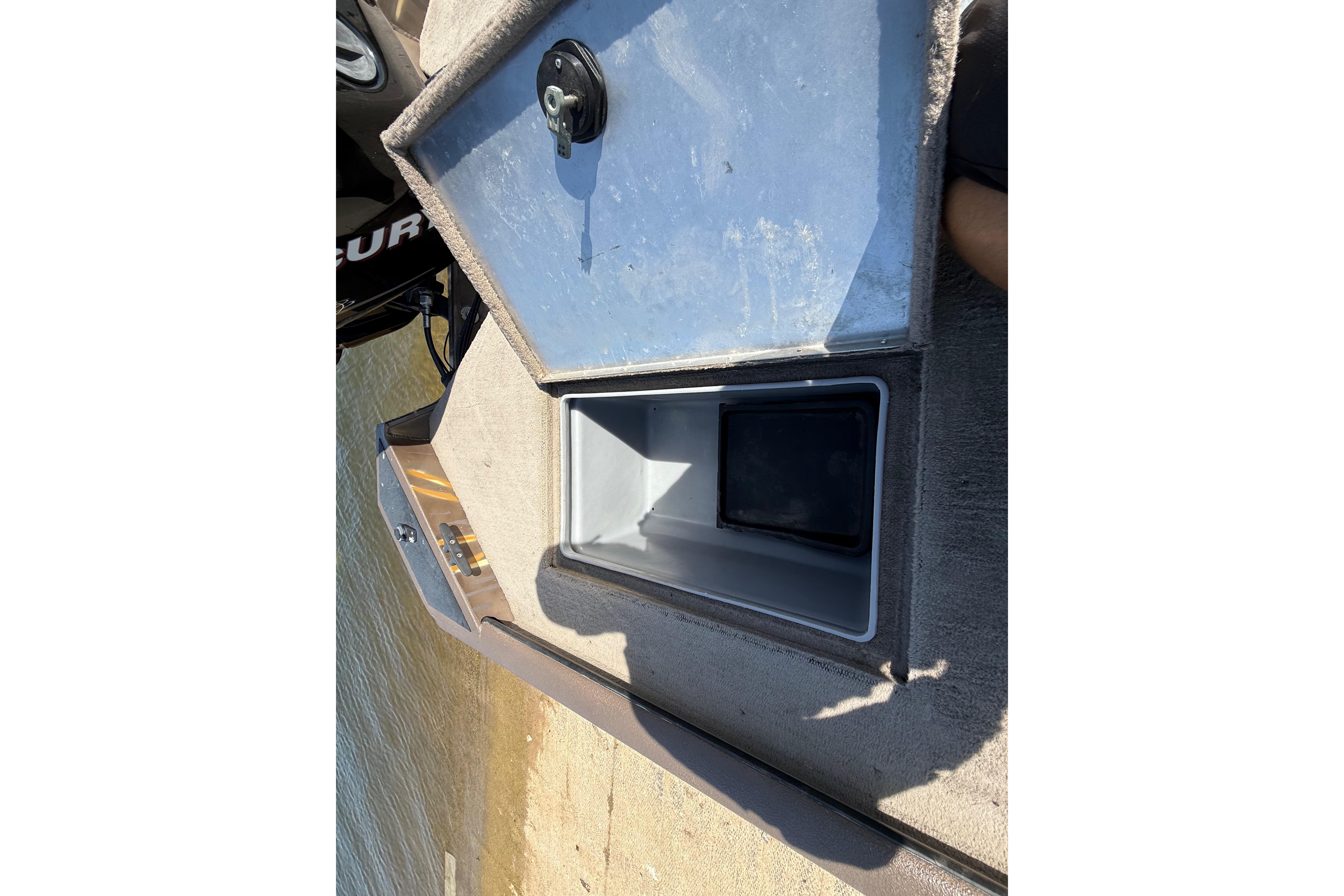Open storage compartment on a 2010 SeaArk Stealth 190 boat, near water.