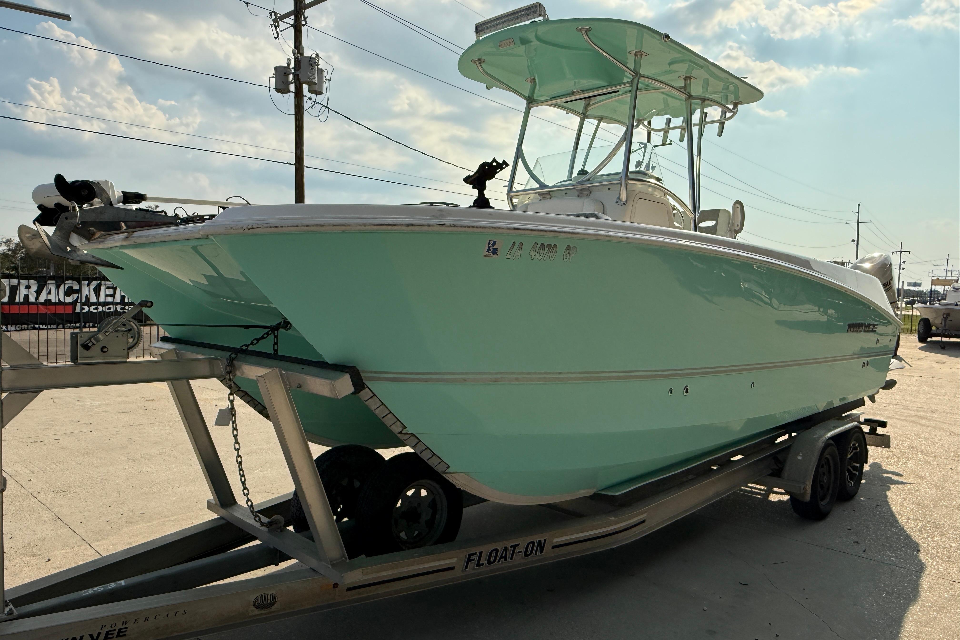 2020 Twin Vee 240 GFX CC boat on trailer, light blue hull, sunny day.