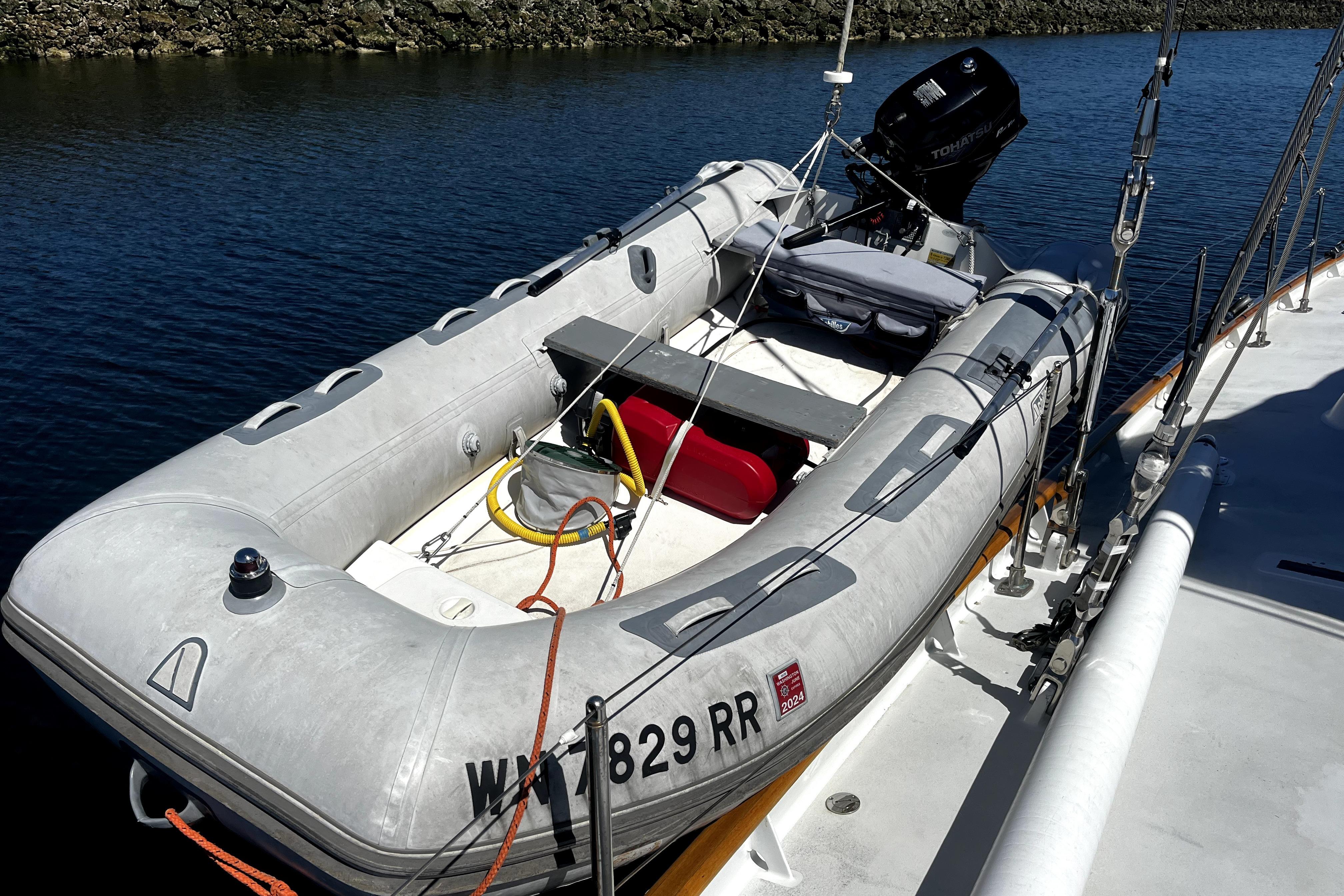 Inflatable boat docked beside Abeking & Rasmussen Tripp 74 yacht, 1968 model, on calm water.