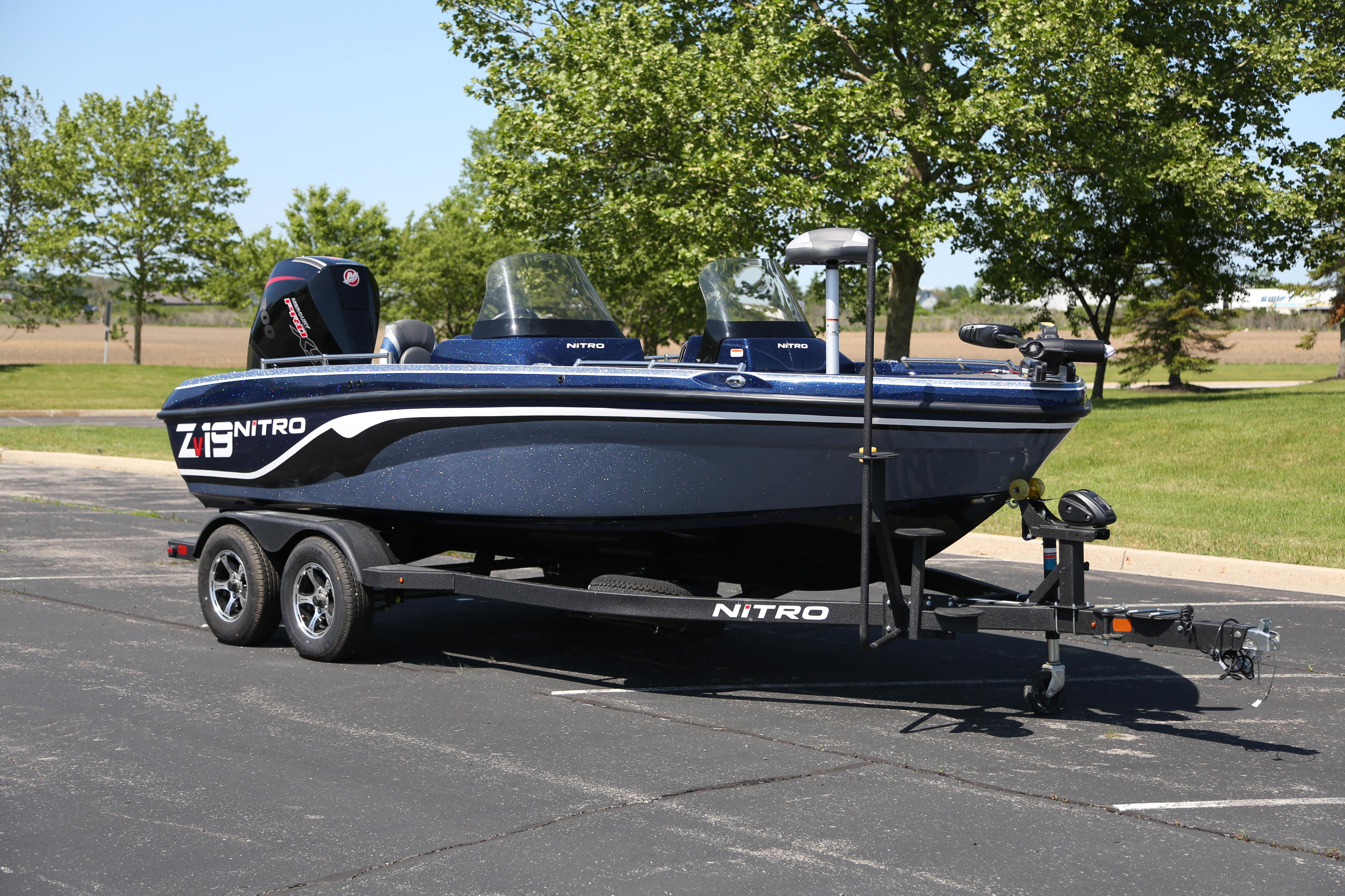 2026 Nitro ZV19 boat on trailer in parking lot, surrounded by trees.