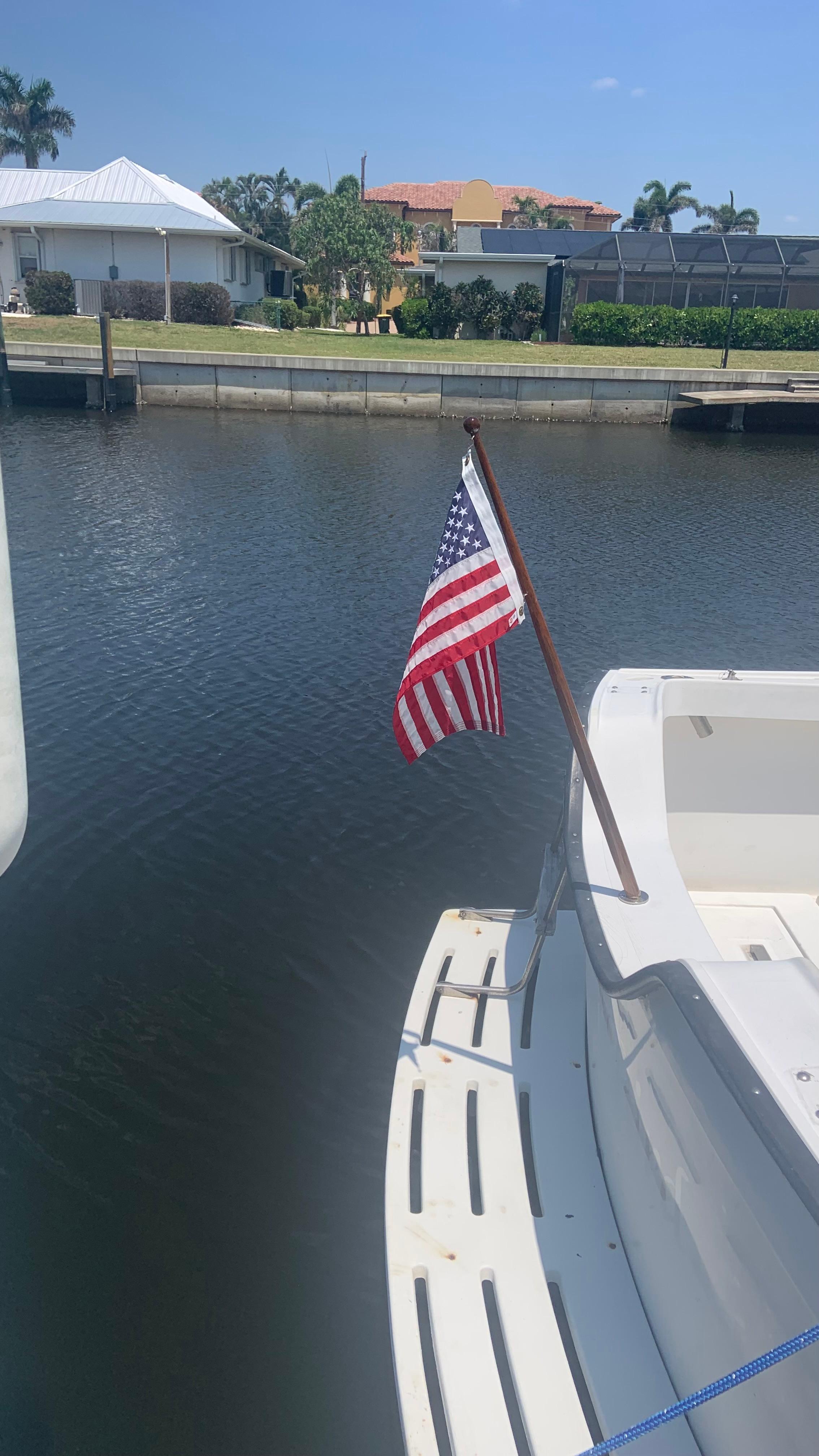 1987 Luhrs Alura 30 boat with American flag docked in a canal.