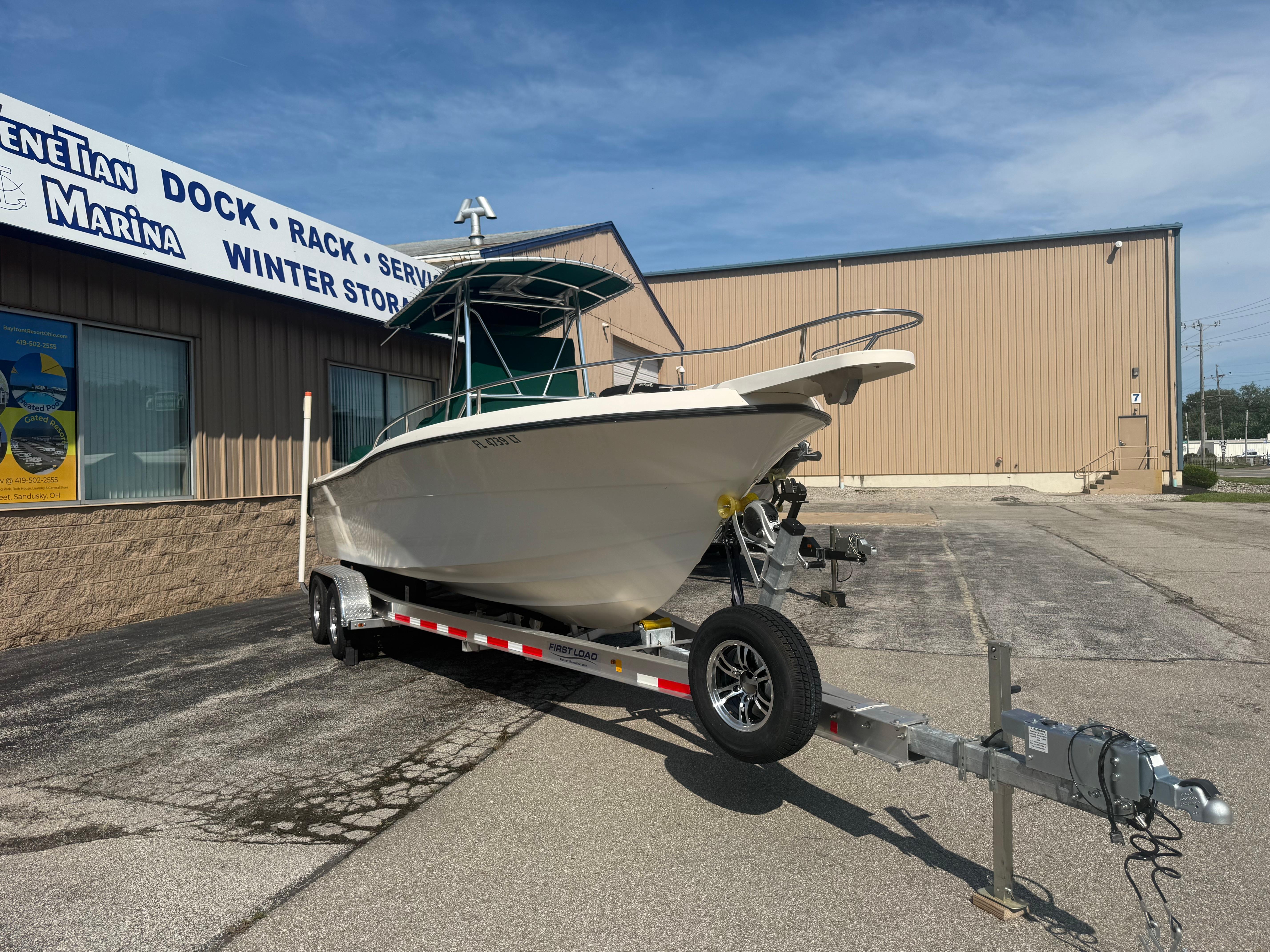 2002 Pursuit 2470 CC boat on trailer outside marina building.