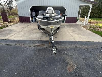A boat on a trailer in front of a garage, ready for transport.