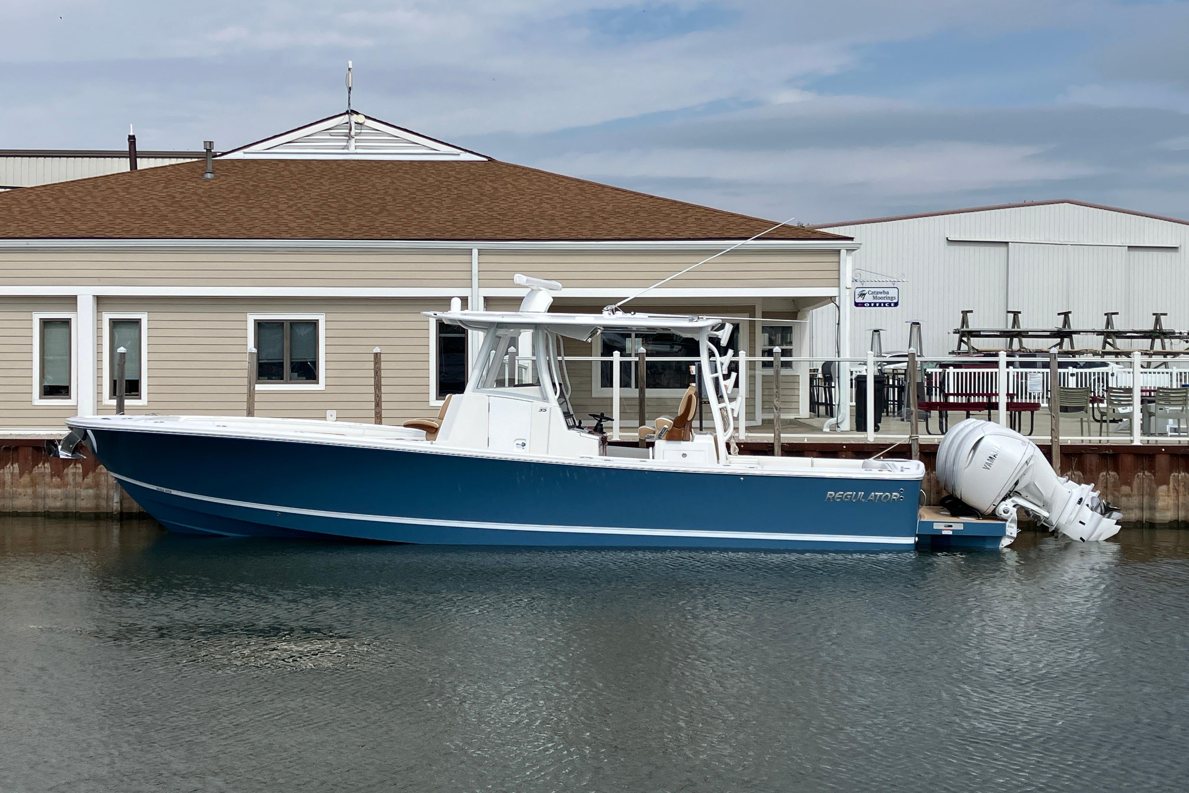 2027 Regulator 35 boat docked by a marina, featuring a sleek blue hull.