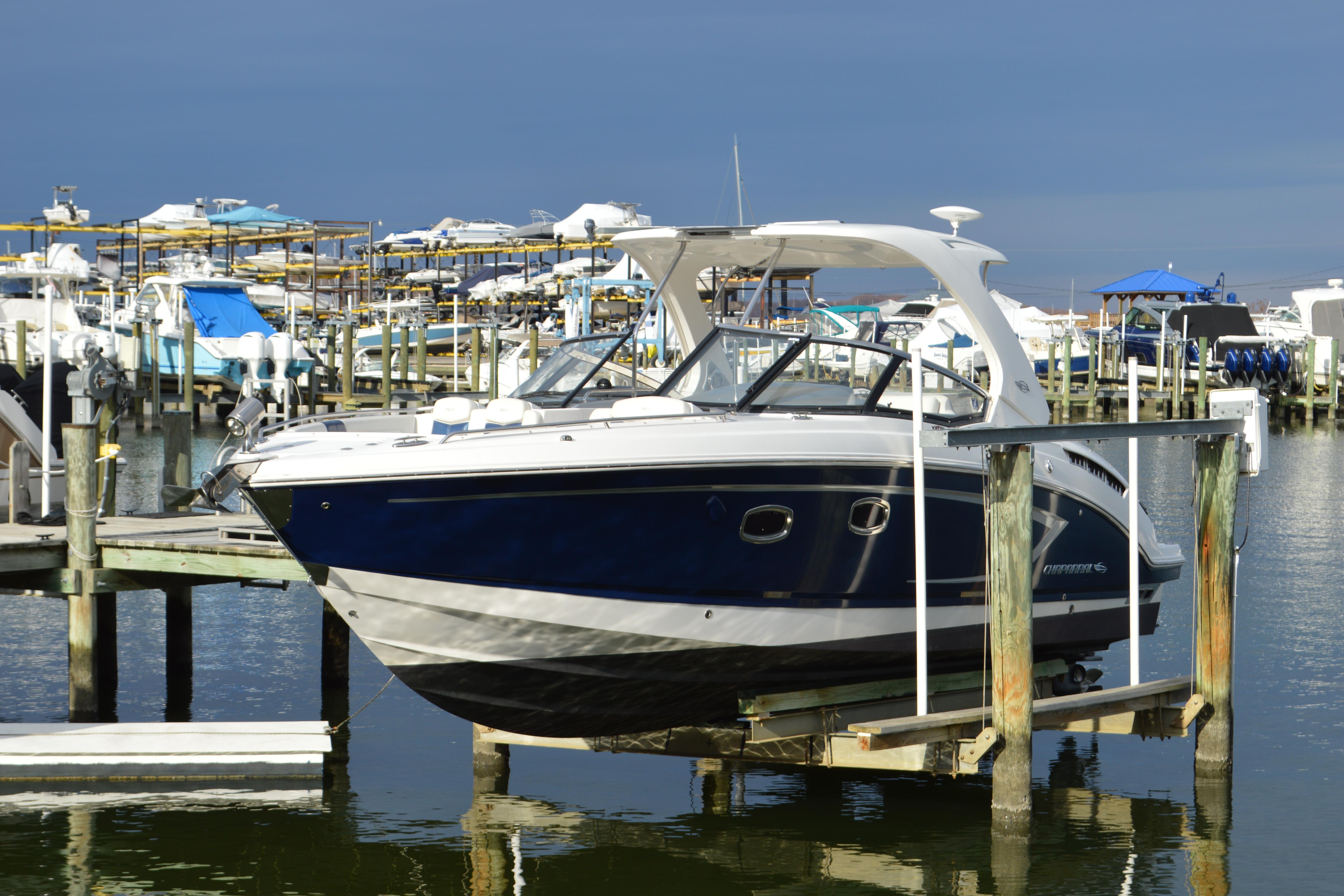 2013 Chaparral 327 SSX boat docked at a marina, surrounded by other vessels.
