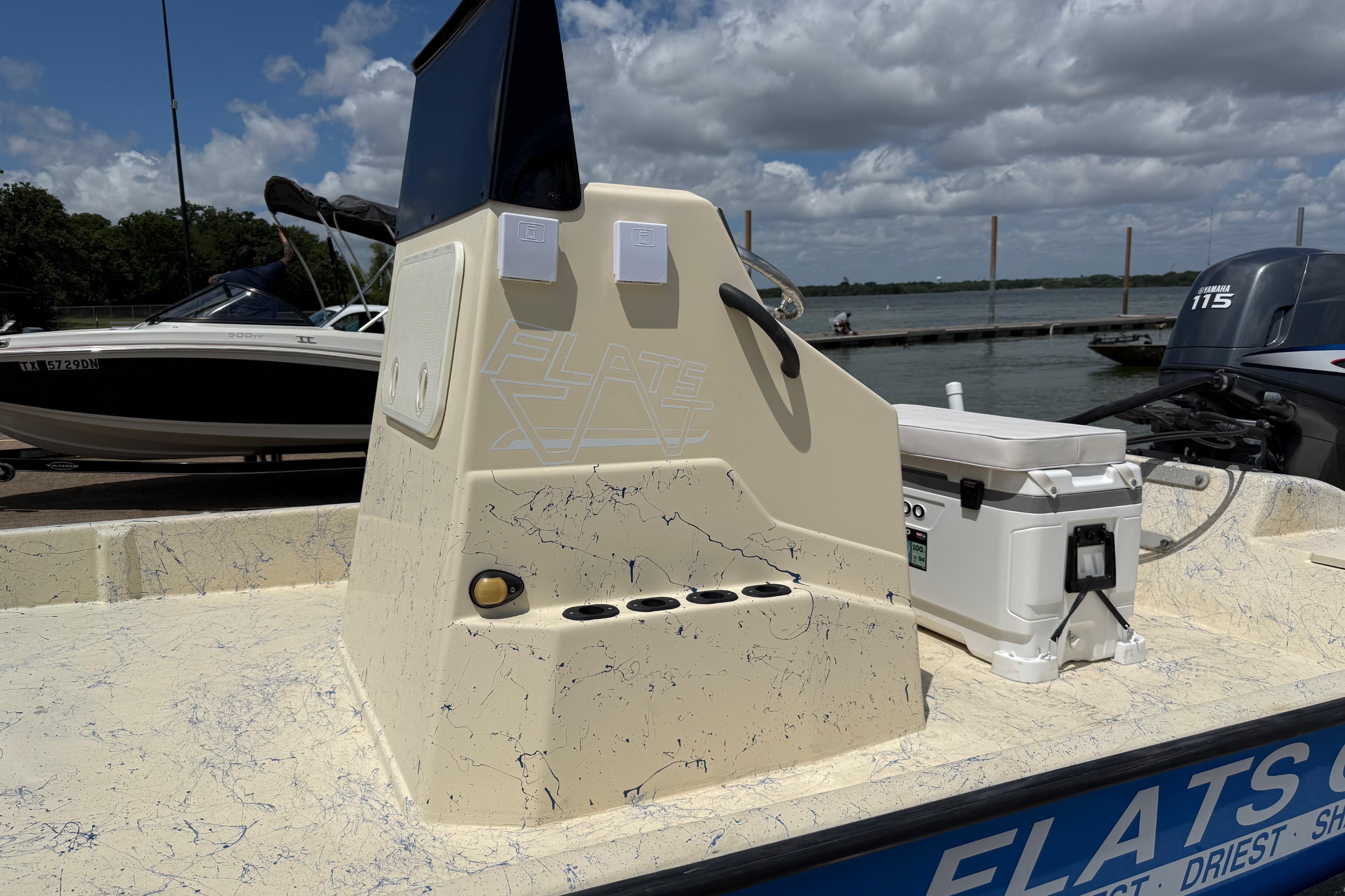 2007 Flats Cat 19 boat console with cooler, docked by the water under a cloudy sky.