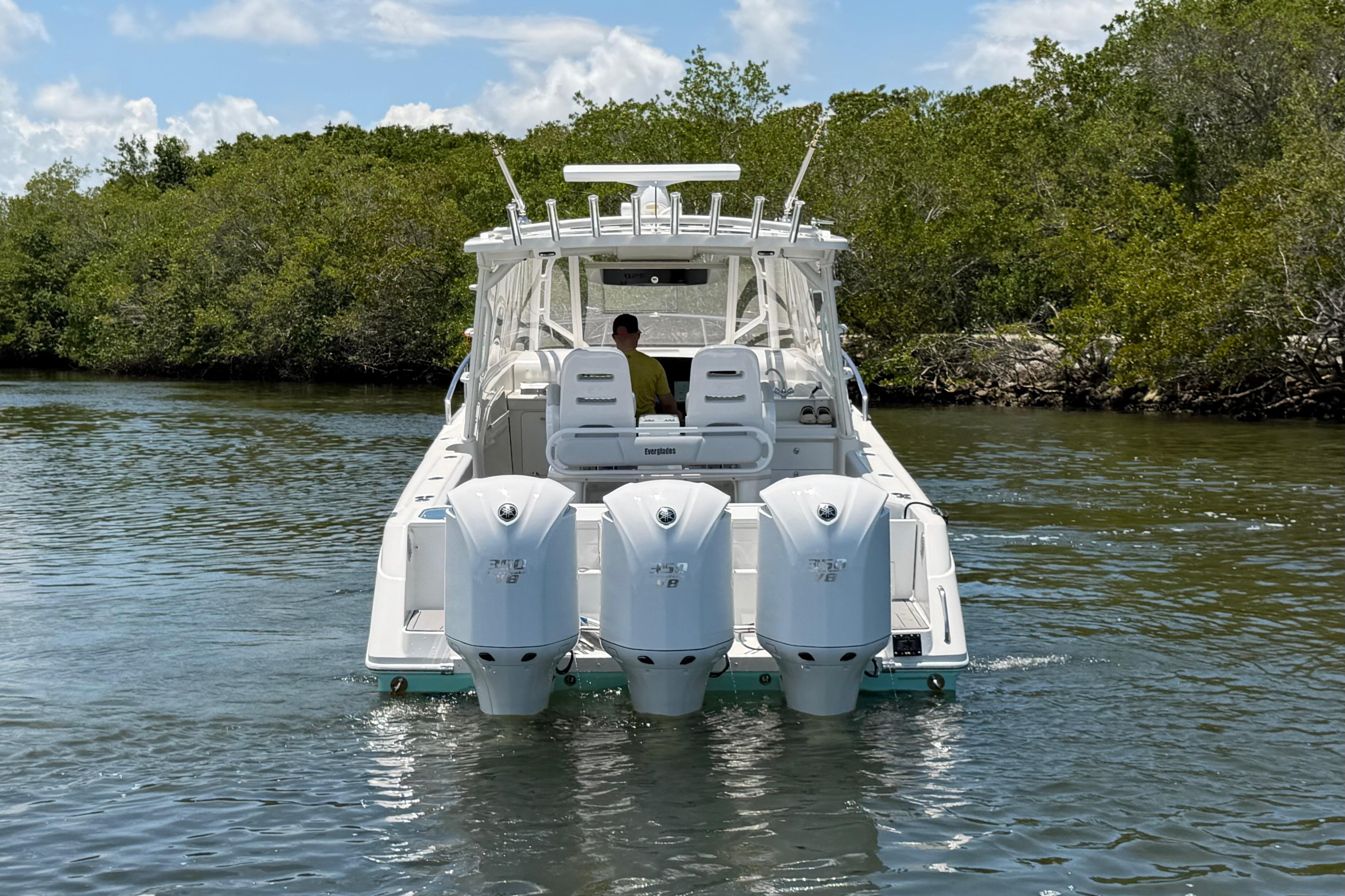 2009 Everglades 350LX boat with triple engines cruising in a scenic waterway.