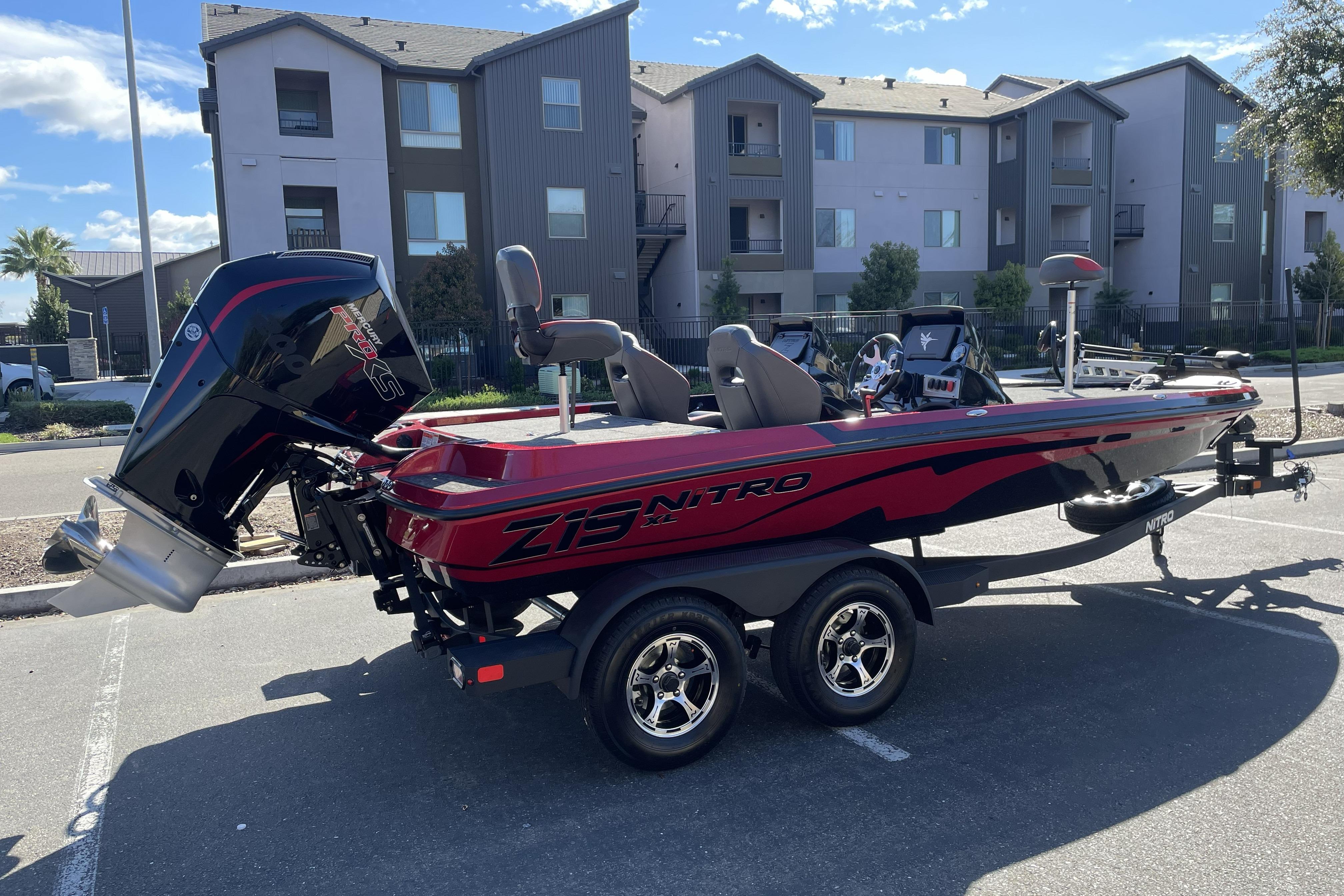 2026 Nitro Z19 XL boat in parking lot, red and black design, modern residential backdrop.