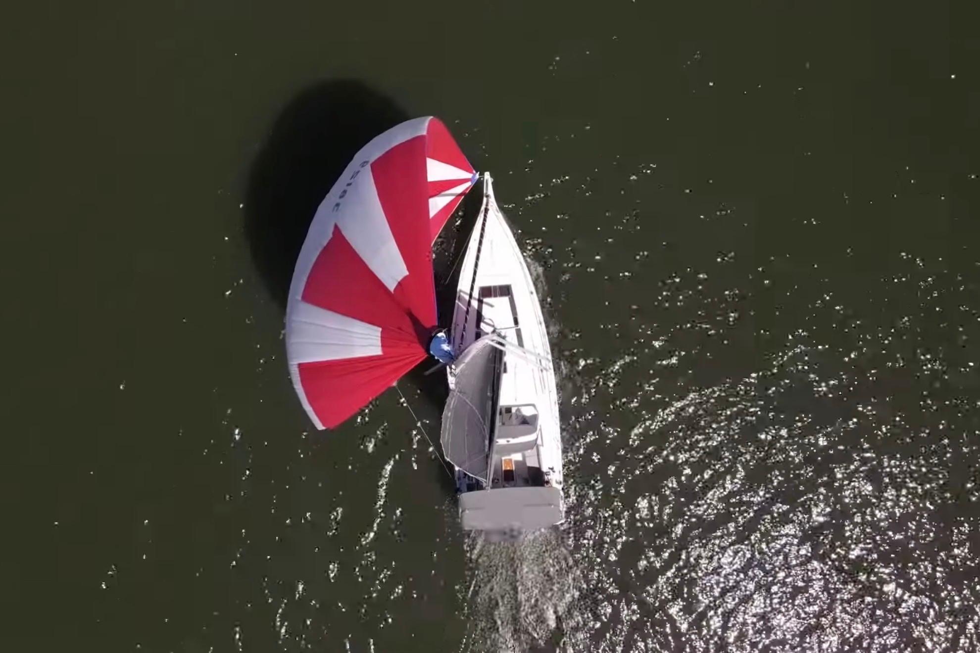 Aerial view of 2020 Beneteau Oceanis 46.1 sailboat with red and white spinnaker.