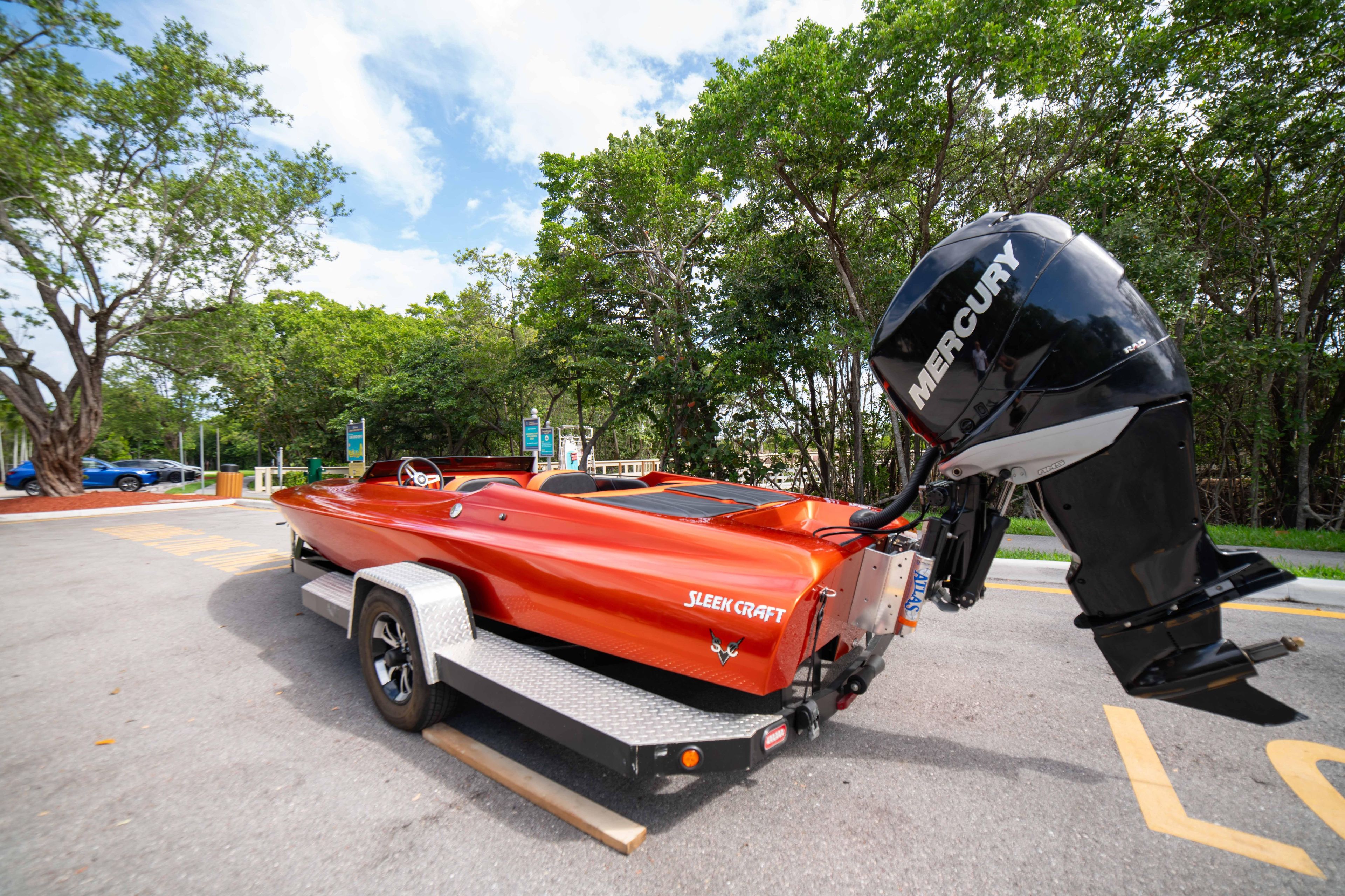 1984 Sleekcraft Aristocrat 20 boat with Mercury engine on trailer, parked near trees.