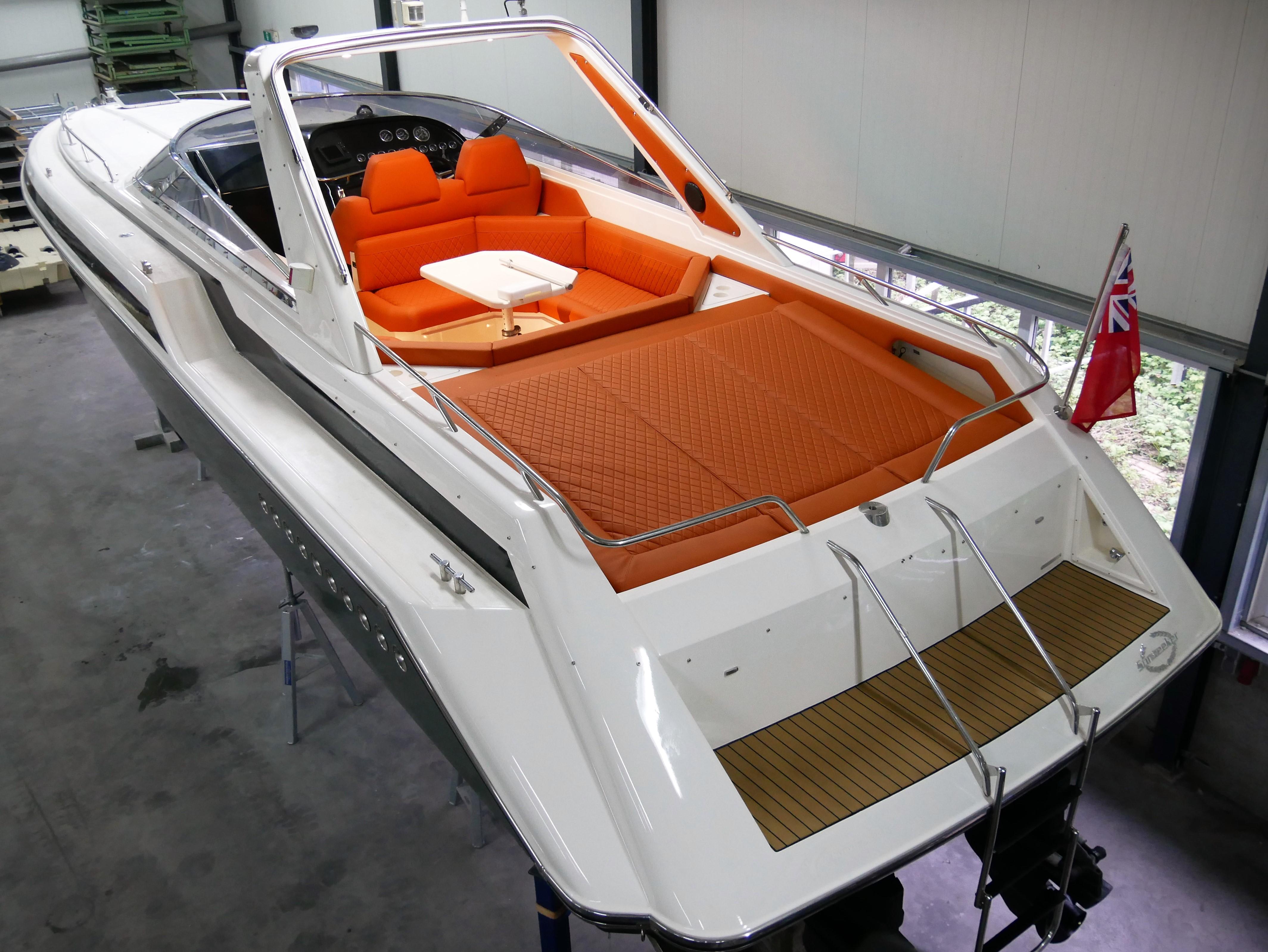 1991 Sunseeker Thunderhawk 43 with orange seating, docked indoors, featuring sleek design and British flag.