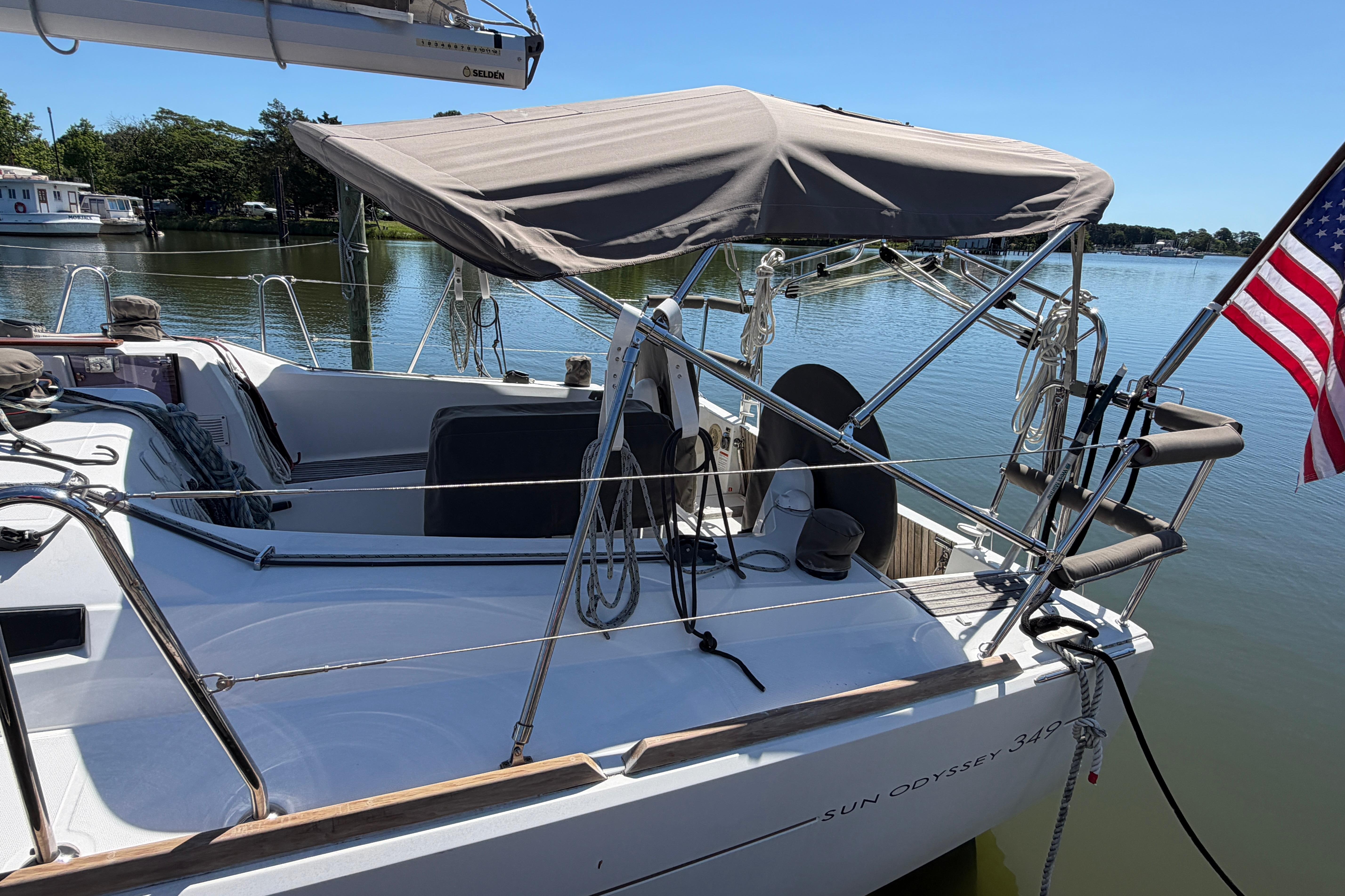 2015 Jeanneau Sun Odyssey 349 sailboat docked on a calm lake with an American flag.