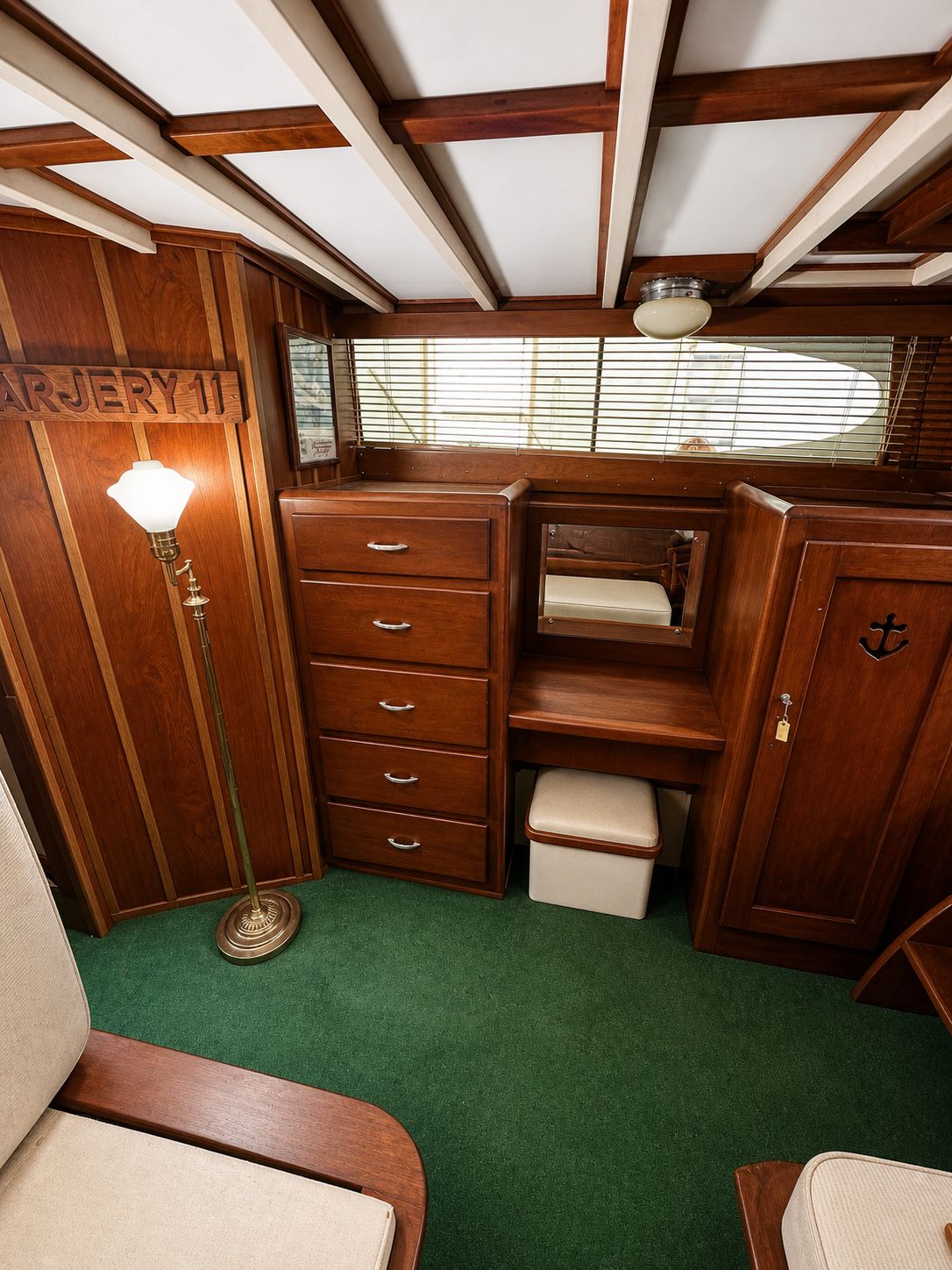 Interior of a 1951 Chris-Craft 50 Catalina yacht, featuring wood furniture and green carpet.