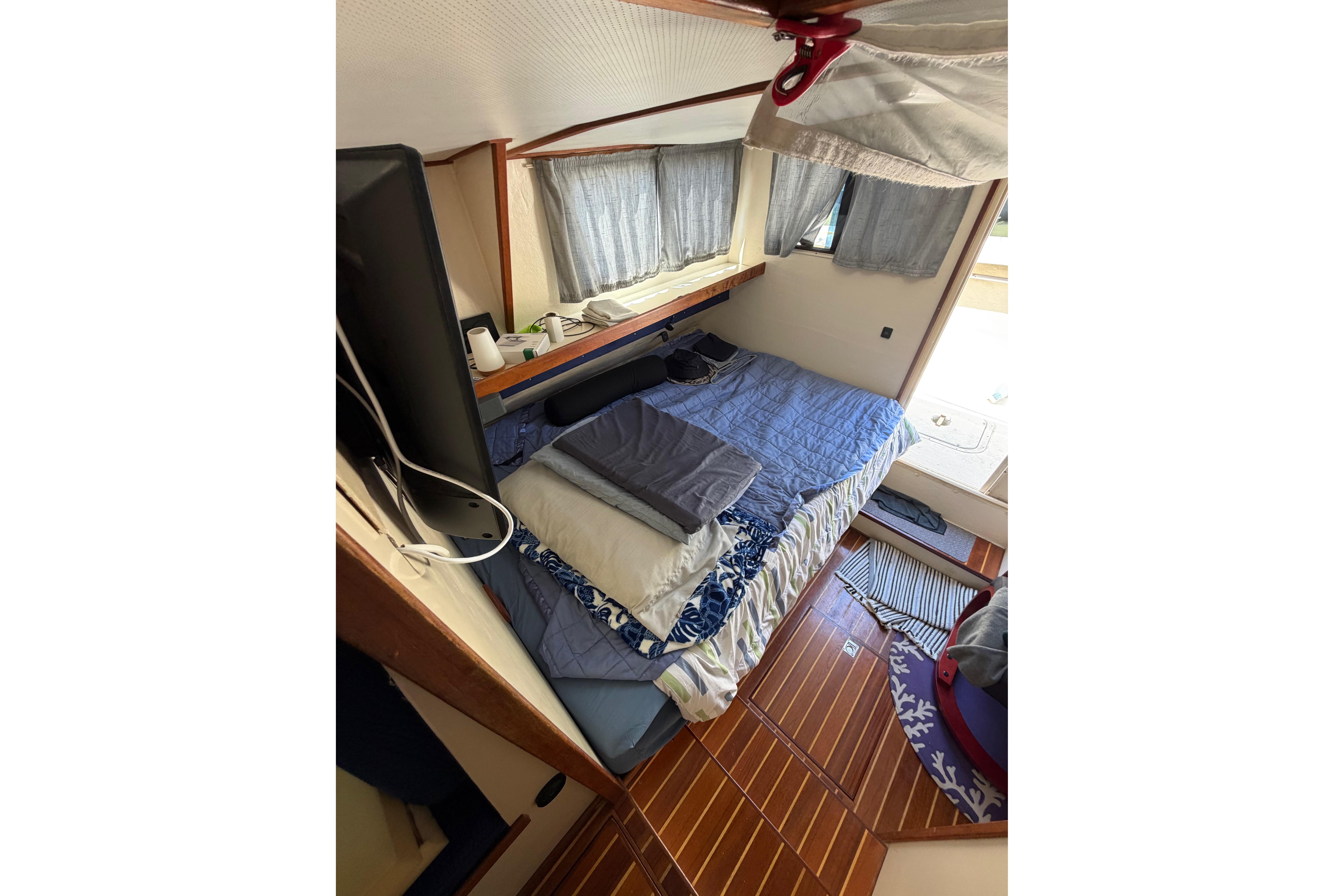 Cozy cabin interior of a 1997 Rosborough Trawler with bed and wooden flooring.