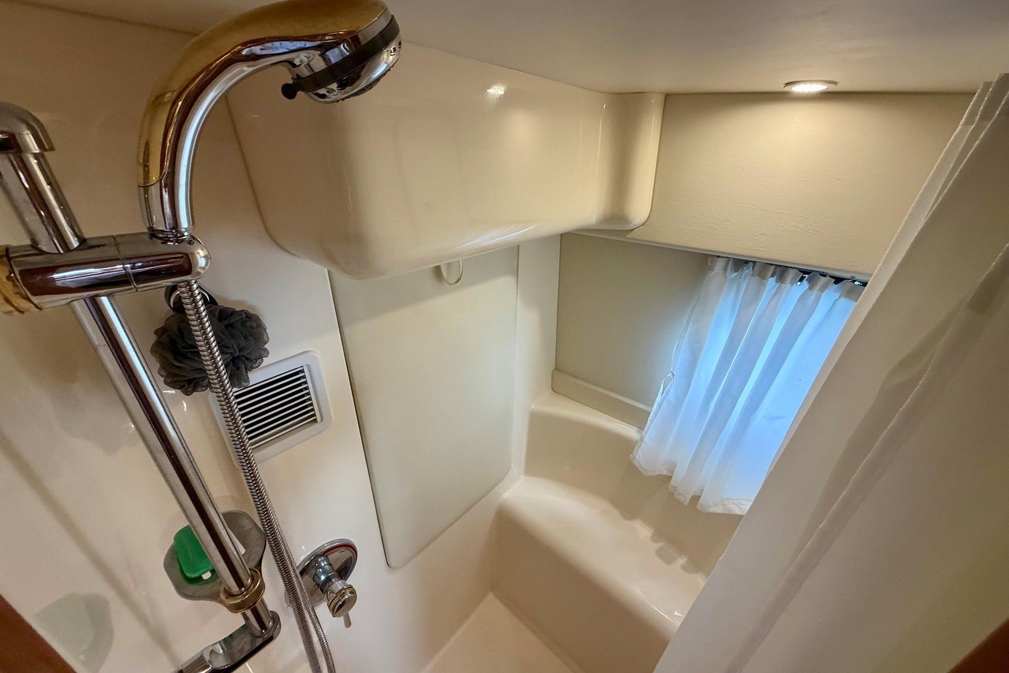 Shower area in 2004 Silverton 39 Motor Yacht with handheld showerhead and window curtain.