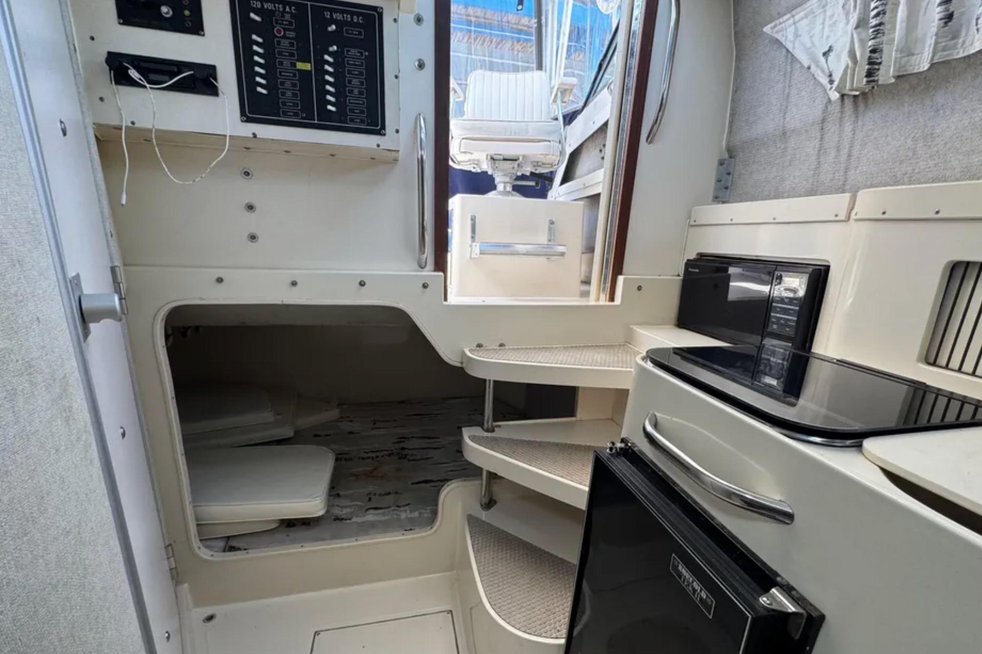 Interior of a 1990 Grady-White Marlin 280 boat, featuring a compact kitchen and sleeping area.