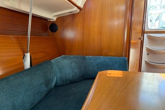 Interior of 2000 Beneteau Oceanis 321 sailboat with wooden paneling and blue cushioned seating.