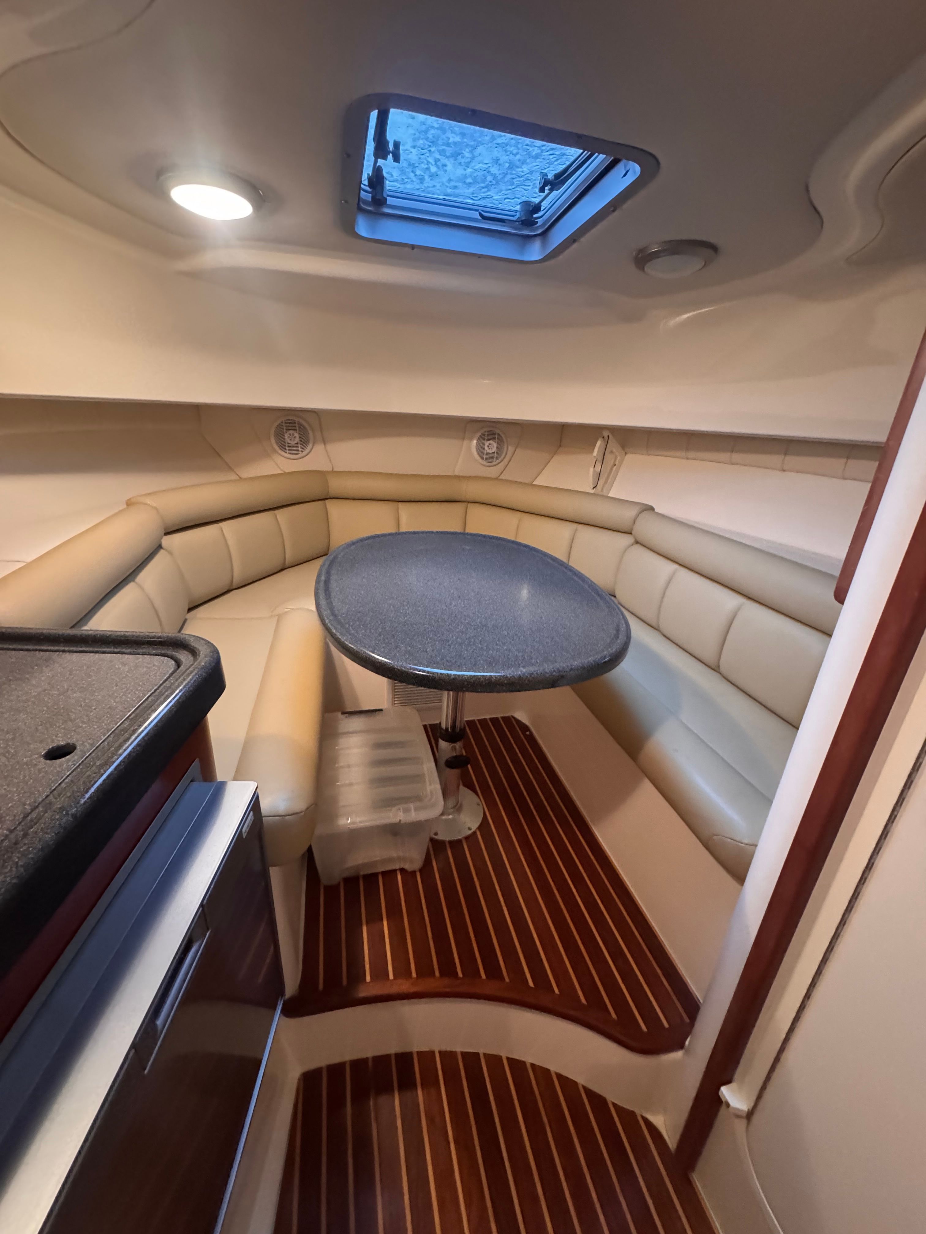 Interior of a 2006 Boston Whaler 305 Conquest with cushioned seating and a table under a skylight.