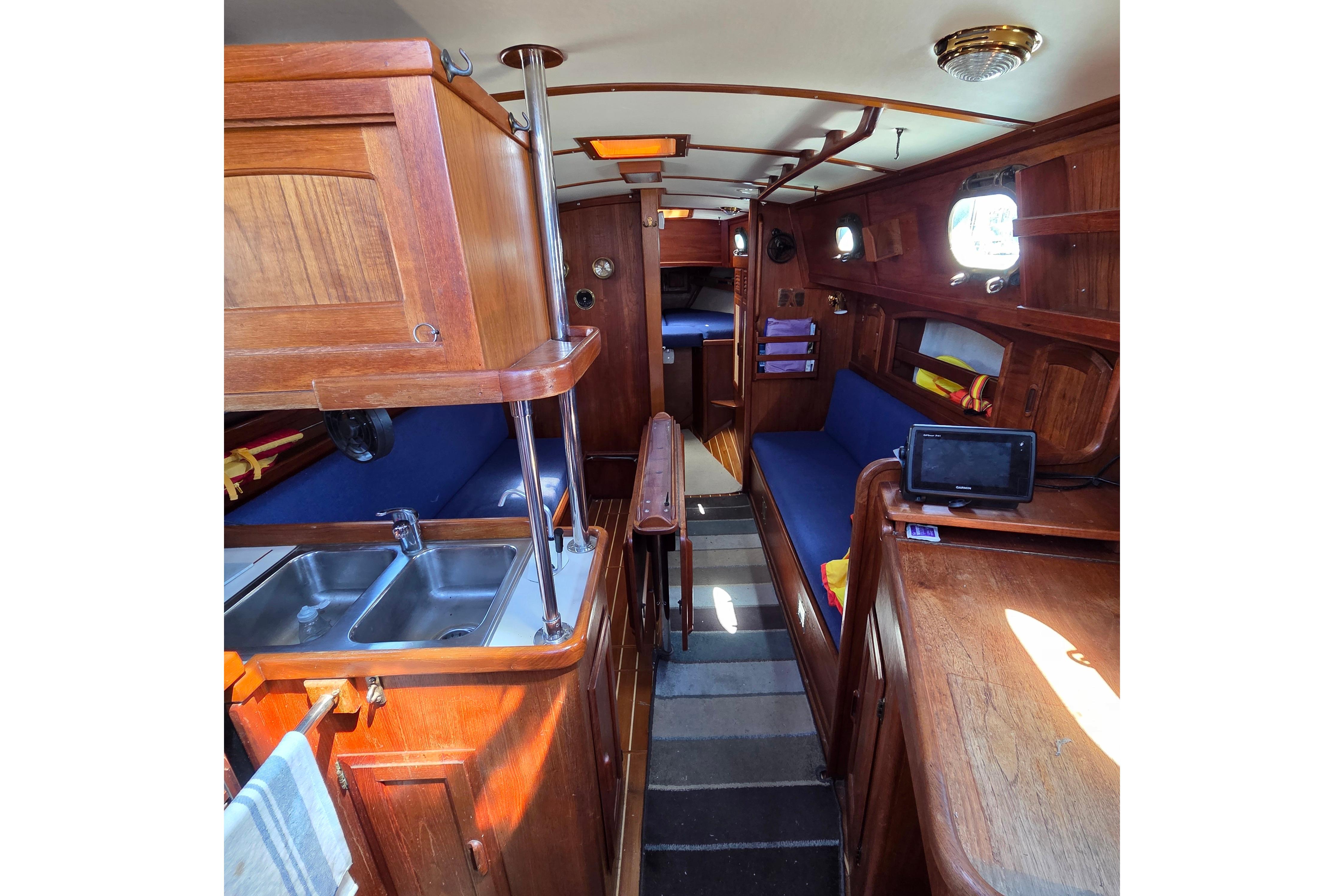 Interior of 1983 Pacific Seacraft 34 sailboat with wooden cabinetry and blue seating.