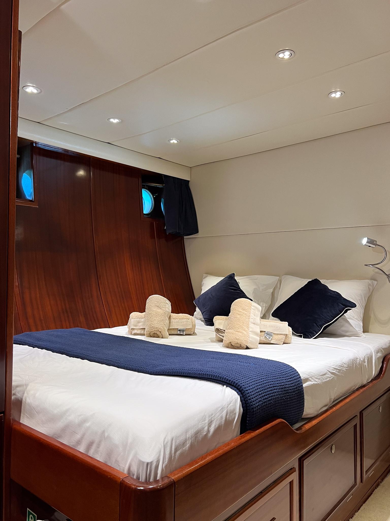 Luxurious cabin interior of 1969 Custom Psarros Shipyard yacht with elegant bedding and wood paneling.