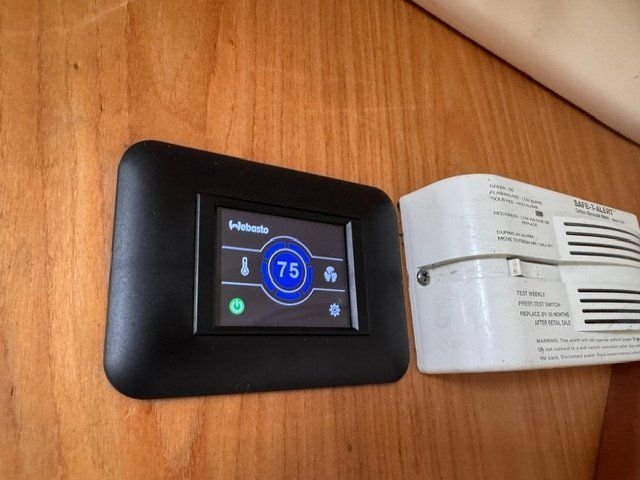 Thermostat and smoke detector on a wooden wall.