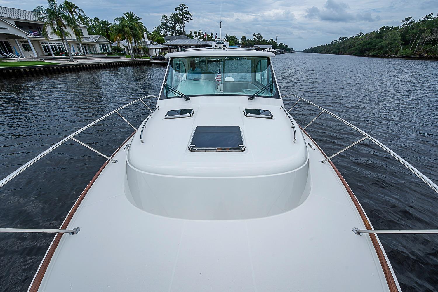 2023 Hinckley Sport Boat 40 X cruising on a scenic river with lush surroundings.